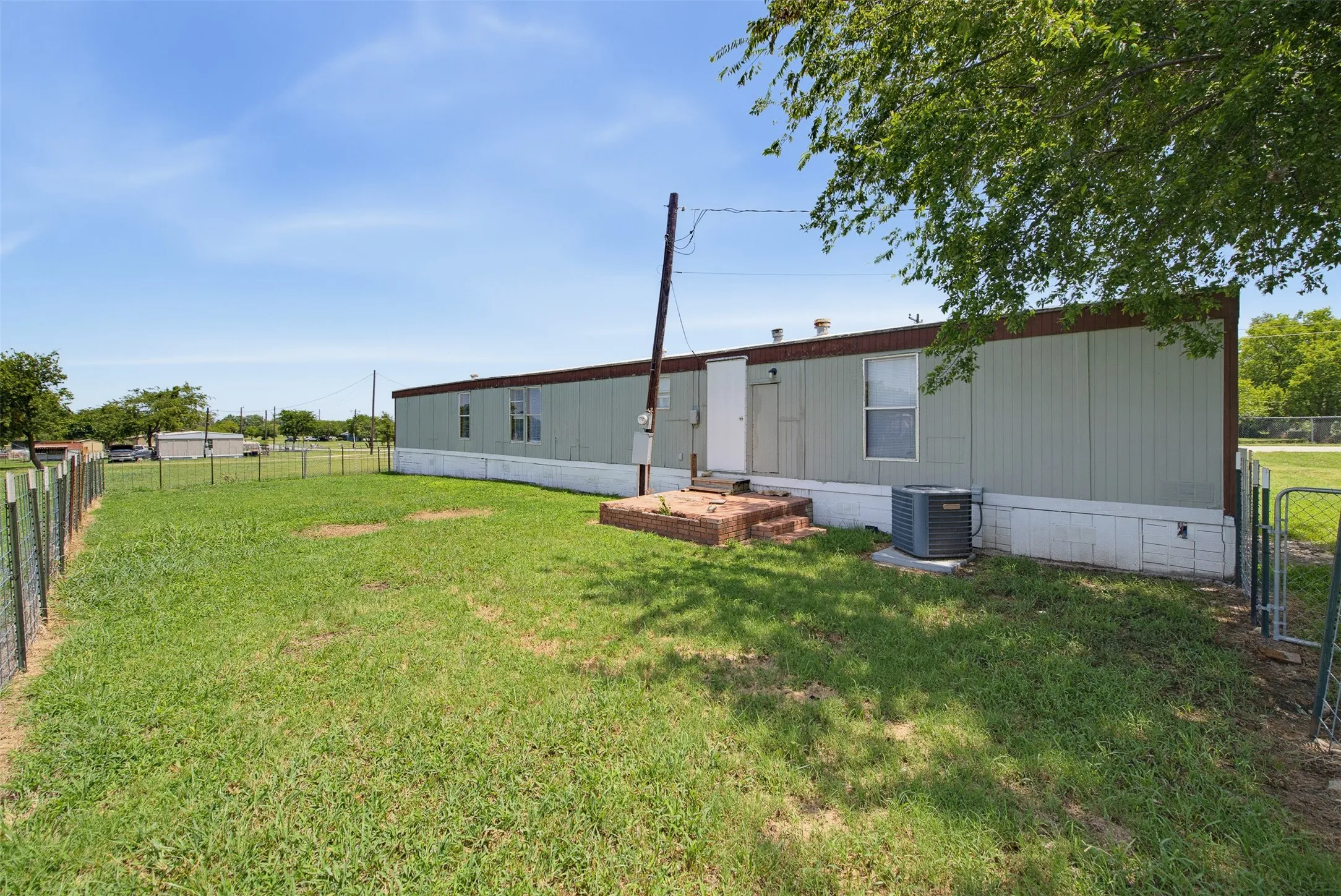 Spacious yard with chain link fencing and mature trees
