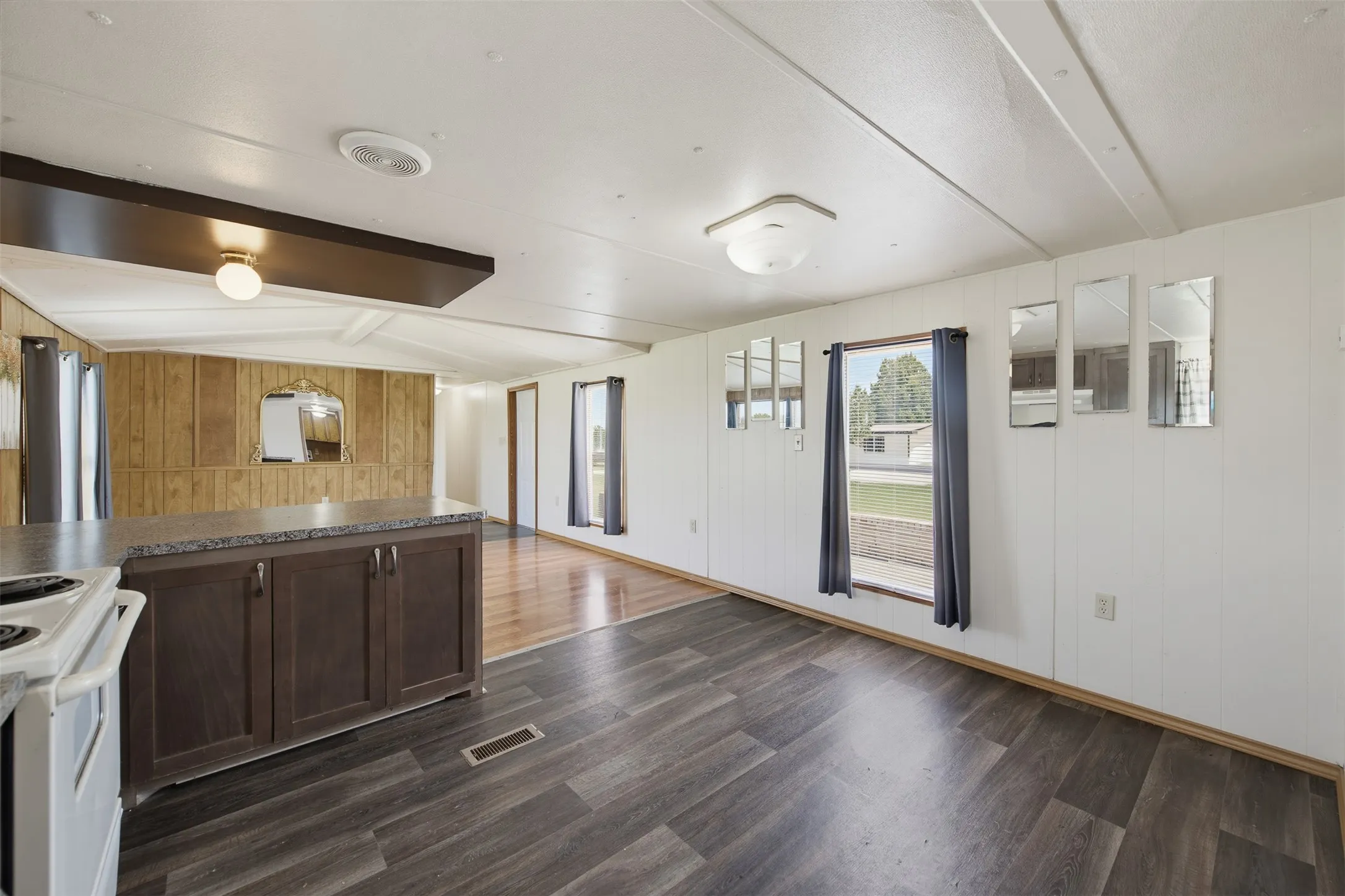 Open-concept interior featuring wood-finish flooring, a kitchen island with storage, and an electric range