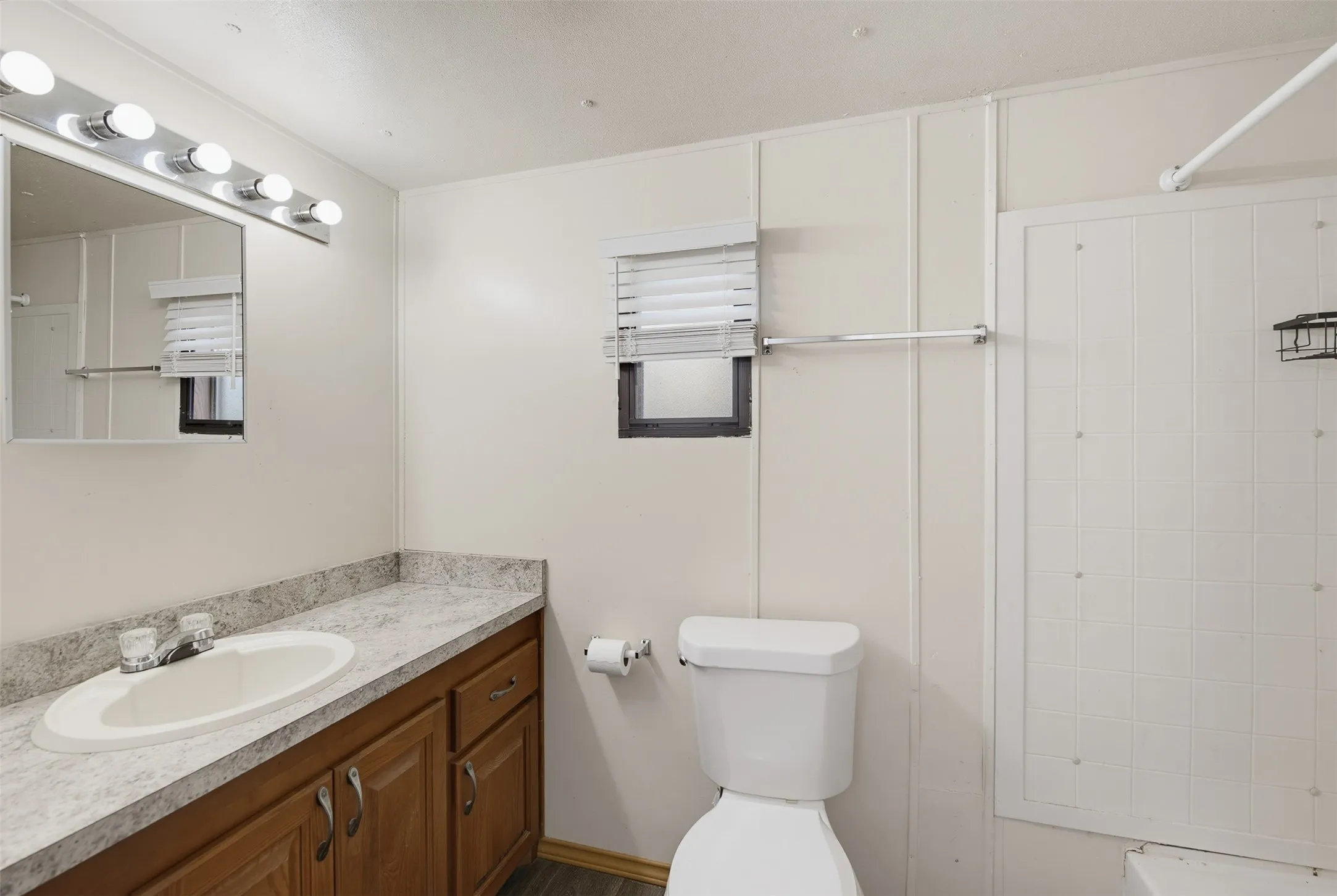 Bathroom vanity featuring a white oval sink, chrome faucet, and a light-toned patterned countertop