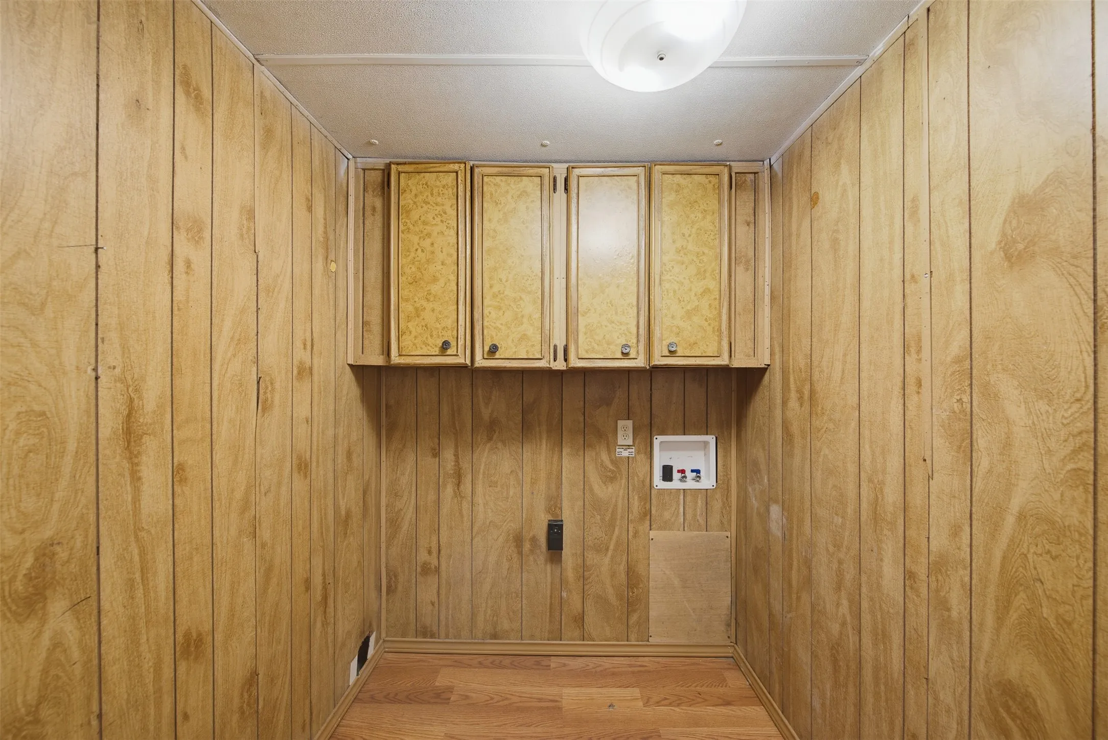 Utility space featuring wood-finish paneling and complementary wood-finish flooring