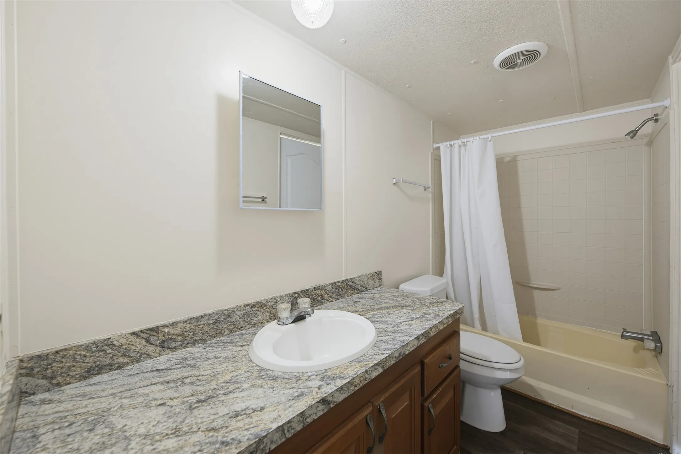 Bathroom featuring a vanity with an integrated sink, a variegated countertop, and wood-finish cabinetry