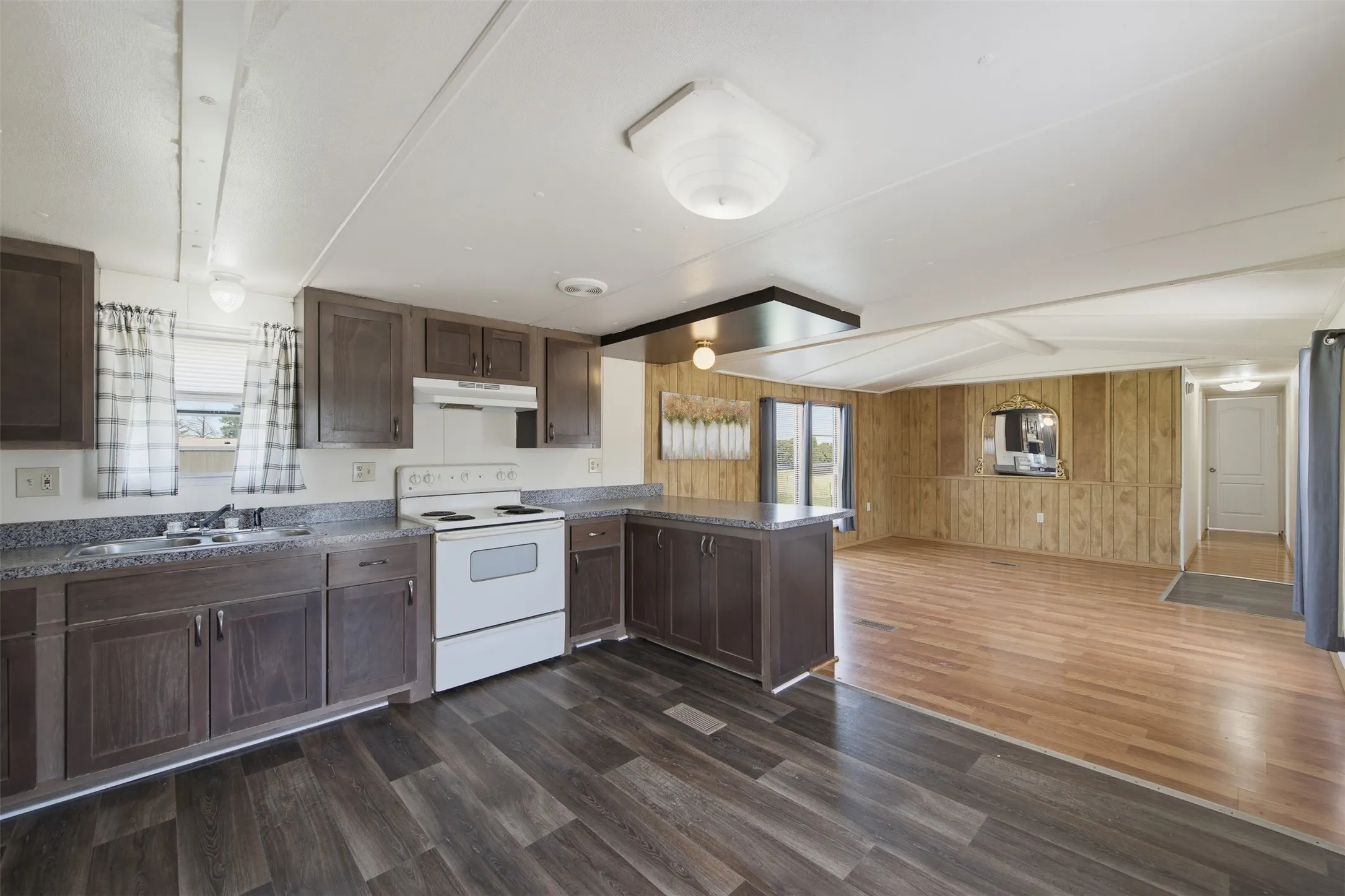 Kitchen featuring dark wood-finish cabinetry, white appliances, and a double basin sink