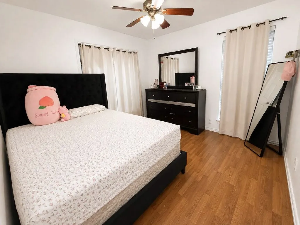 Room featuring wood-finish flooring, a ceiling fan, and white walls