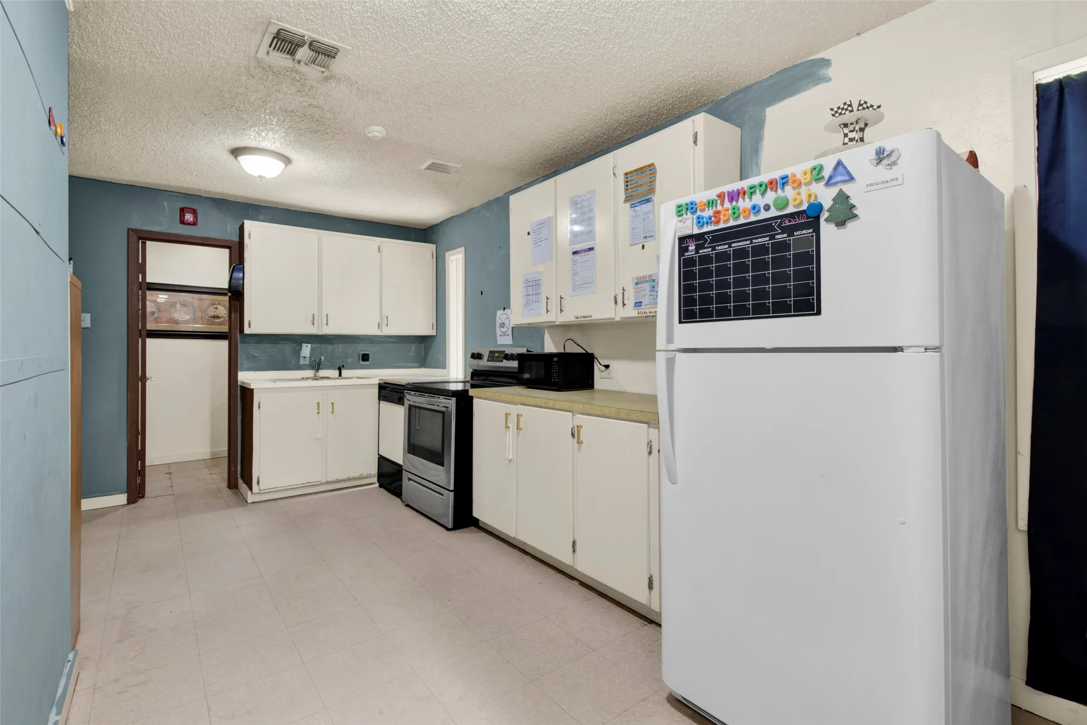 Kitchen featuring white cabinetry, laminate countertops, vinyl flooring, a stainless steel electric range, and a white refrigerator