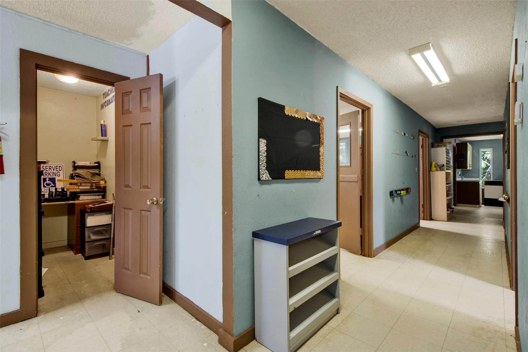Hallway featuring light blue walls, brown trim, and linoleum flooring