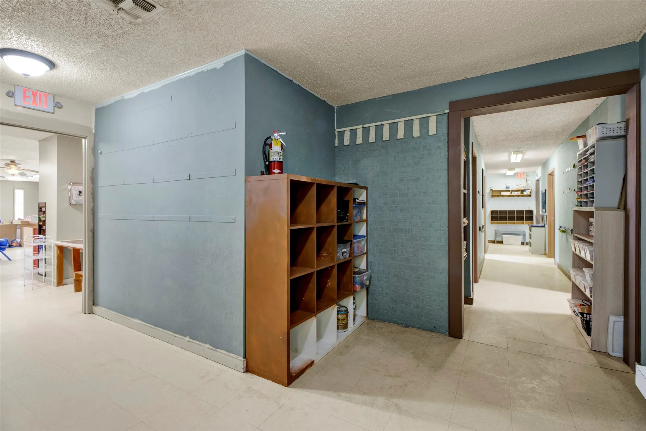 Interior hallway featuring light-colored flooring, multiple doorways with wood-finish trim, and recessed lighting