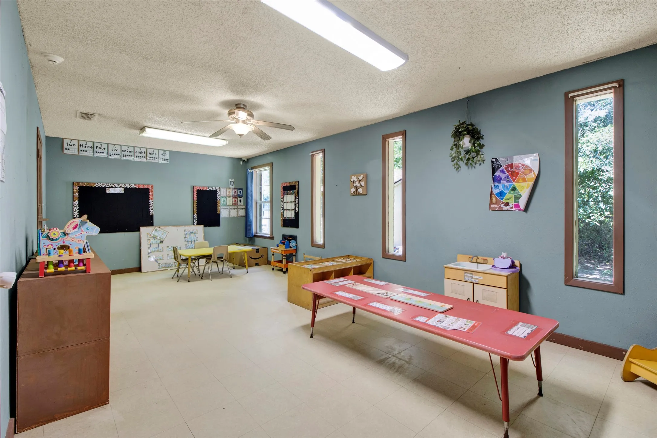 Spacious interior room featuring light-colored flooring, blue painted walls, and multiple narrow windows with brown trim
