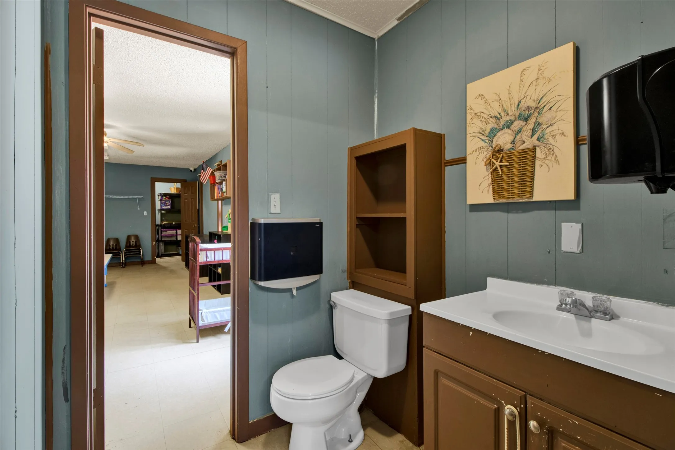 Bathroom with a white toilet, a brown vanity with an integrated sink, and board and batten wall paneling
