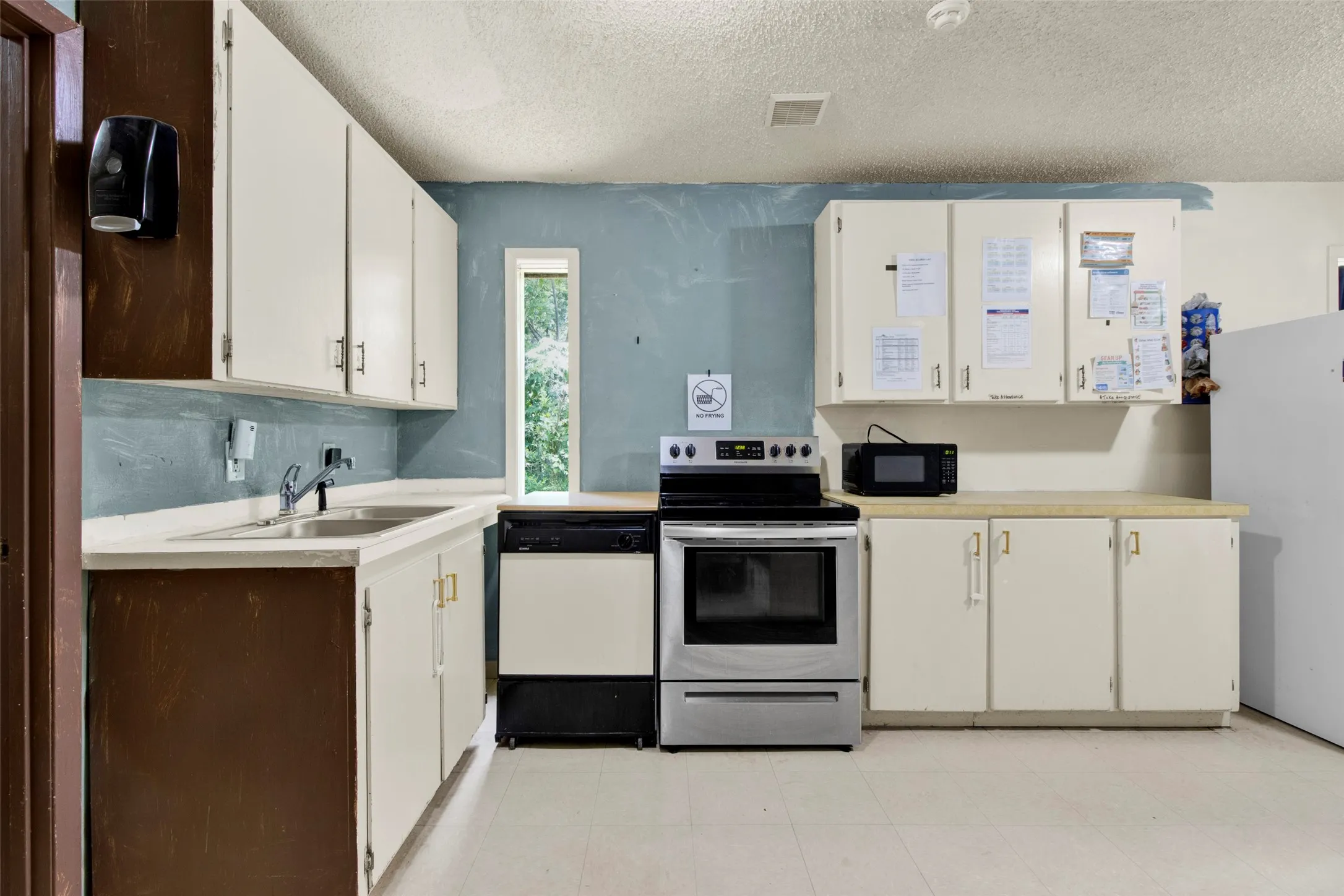 Kitchen featuring white cabinetry, light countertops, and a double basin stainless steel sink