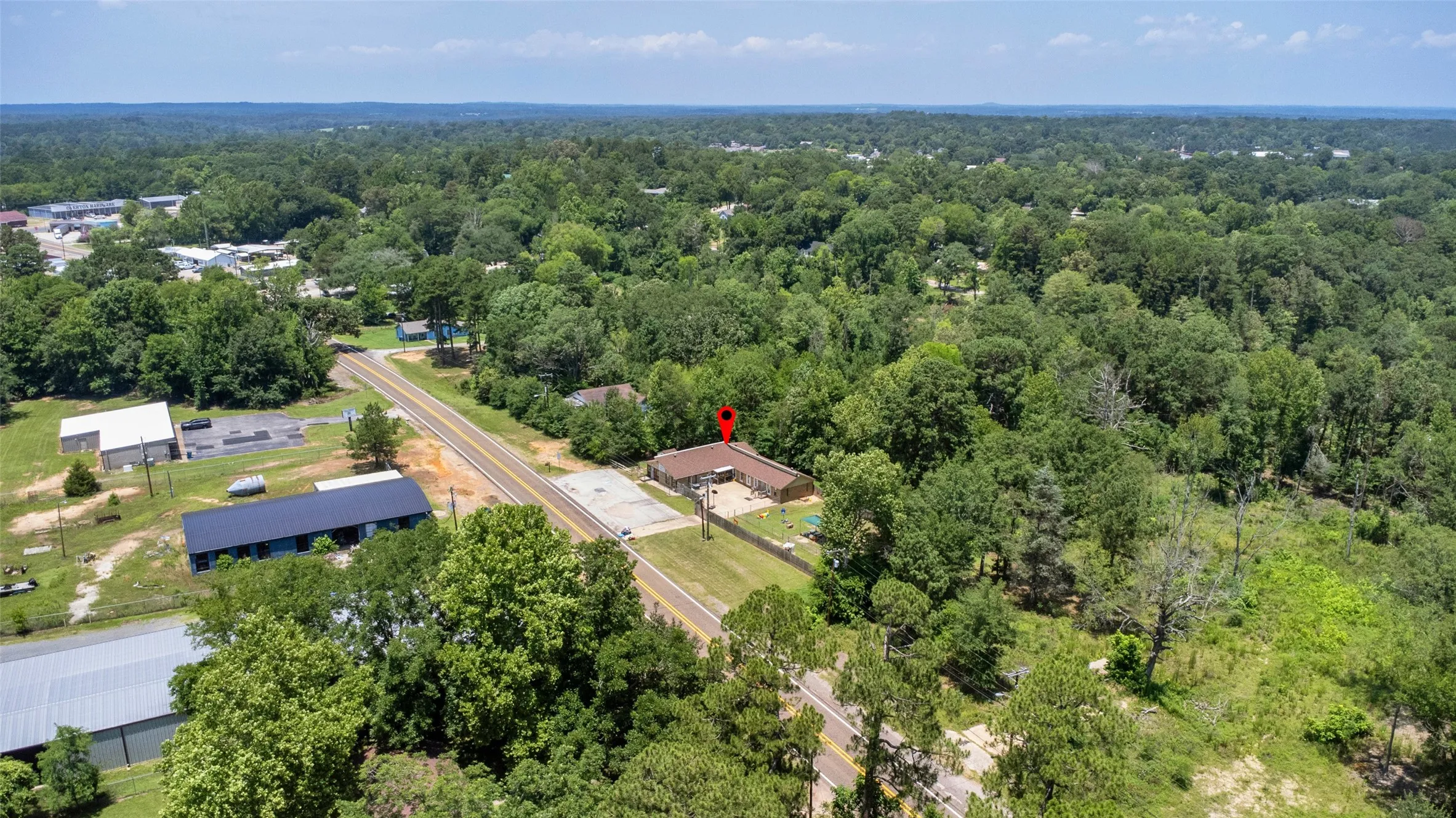 Aerial perspective showcasing the property with extensive tree coverage and proximity to a paved road