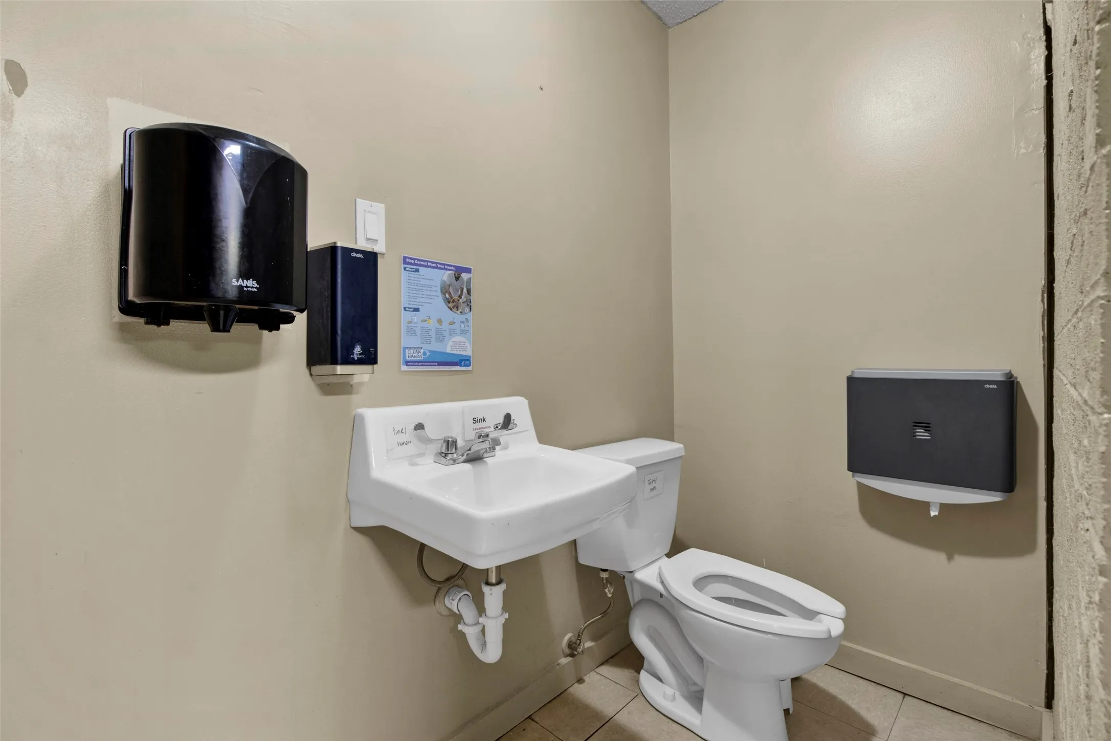 Wall-mounted porcelain sink with chrome fixtures, white toilet, and neutral-toned walls