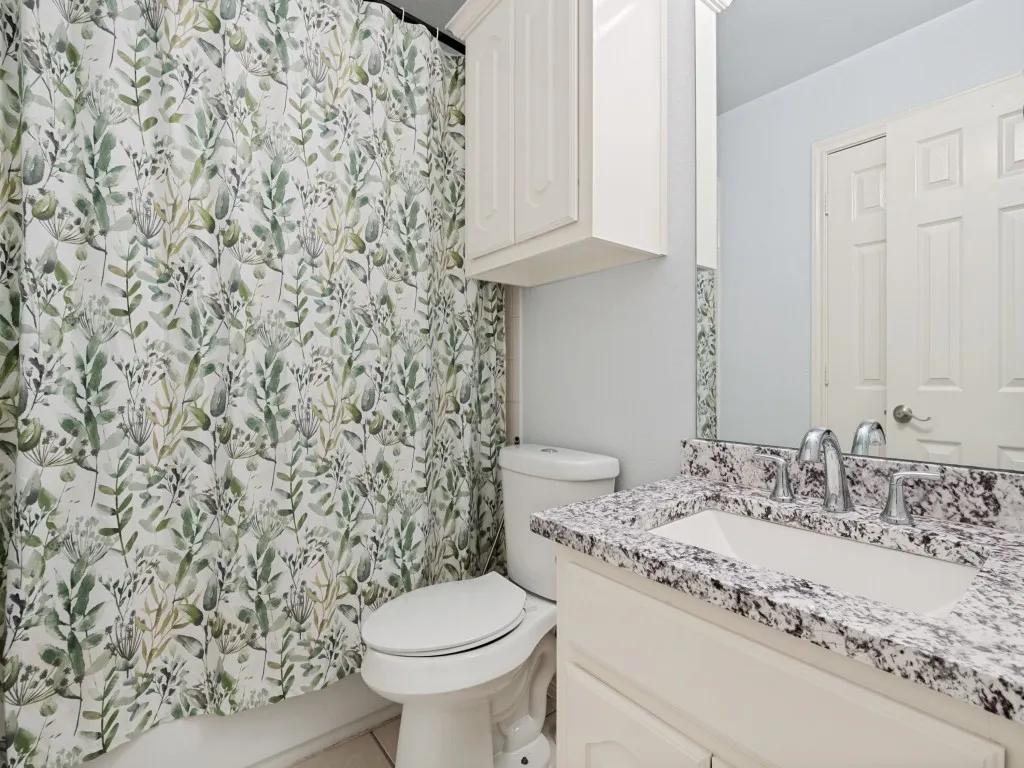 Bathroom featuring a white vanity with a speckled countertop, an integrated sink, and chrome fixtures