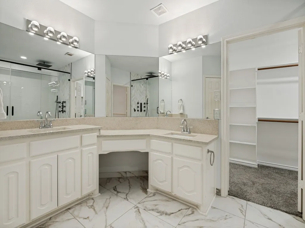 Dual vanity with white cabinetry, light-toned countertops, and chrome fixtures