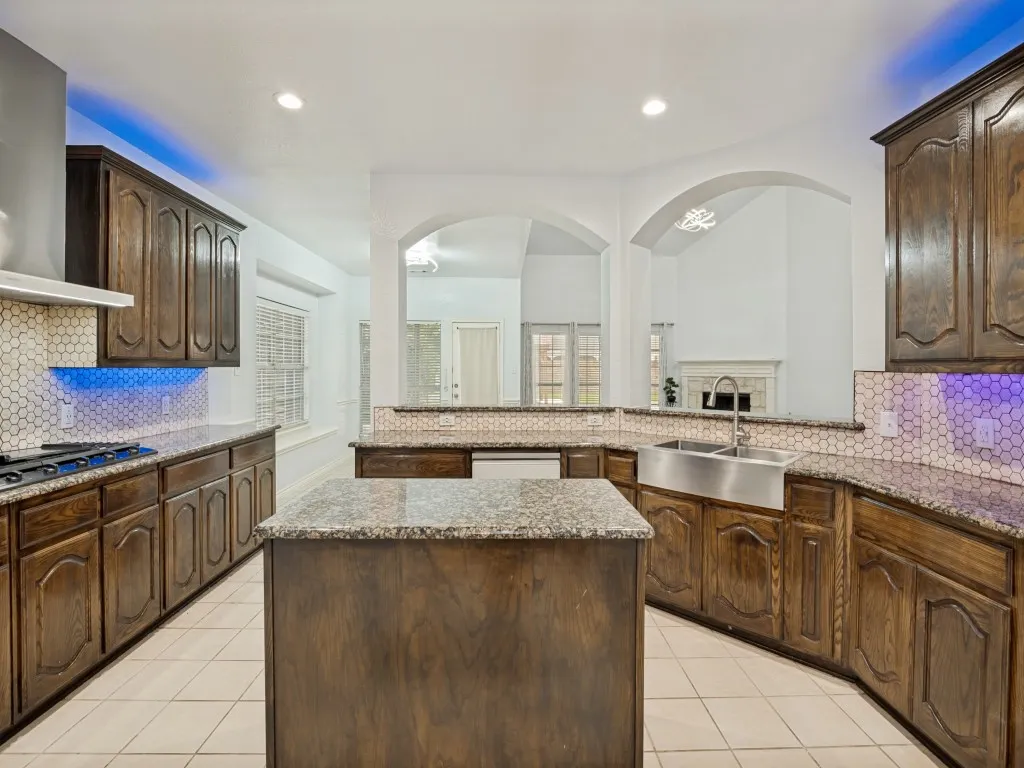 Spacious kitchen featuring dark wood cabinetry, granite countertops, and a hexagonal tile backsplash