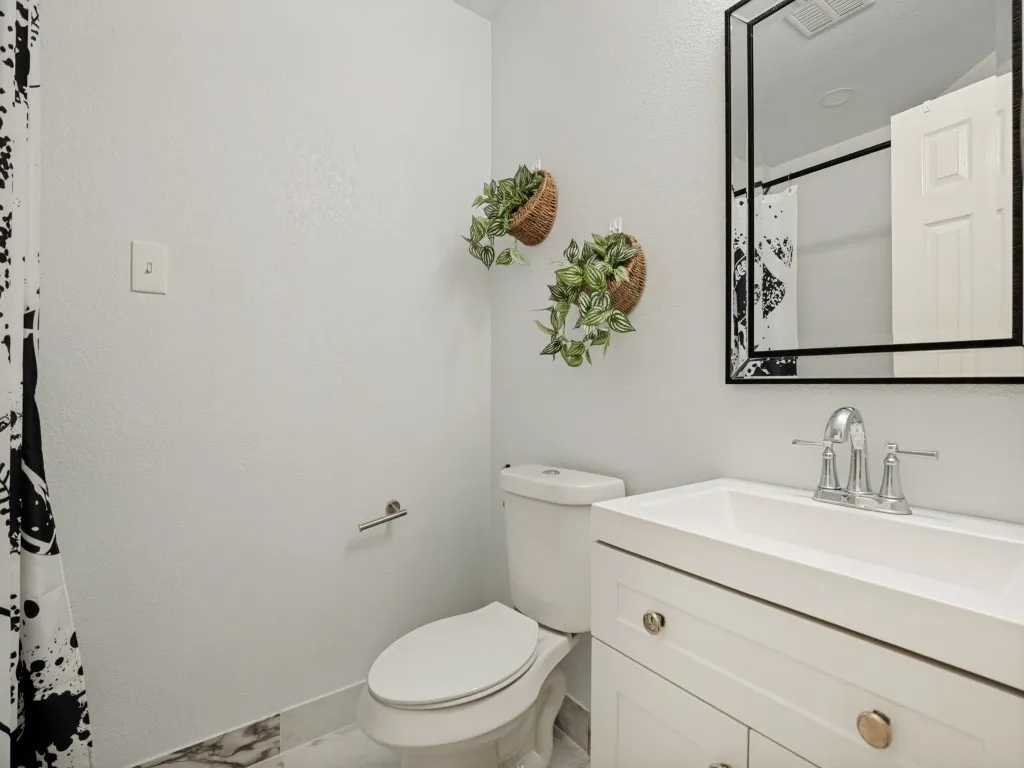 Bathroom featuring a white vanity with integrated sink, chrome faucet, and a geometric-framed mirror