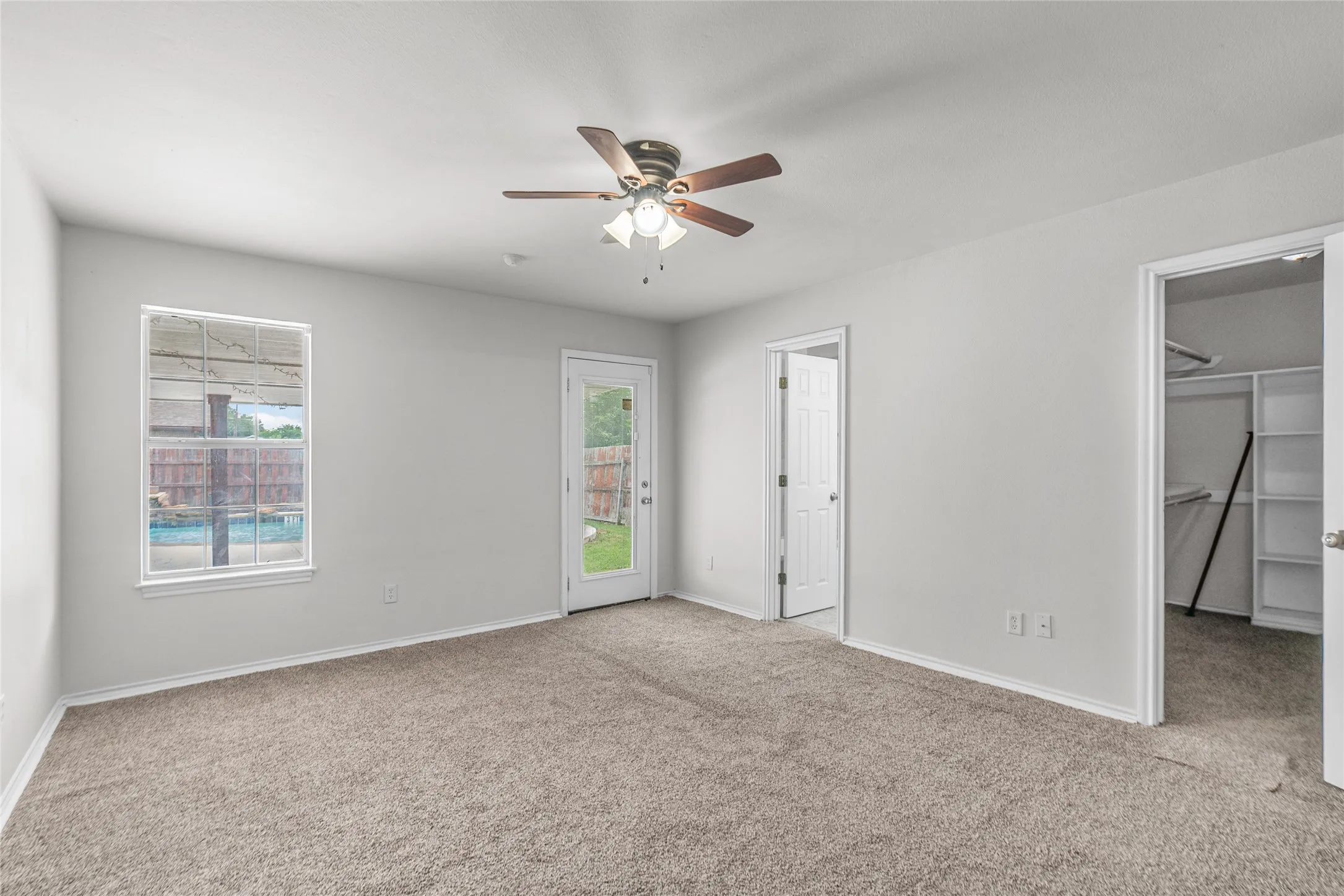 Primary bedroom with plush carpet flooring and a ceiling fan