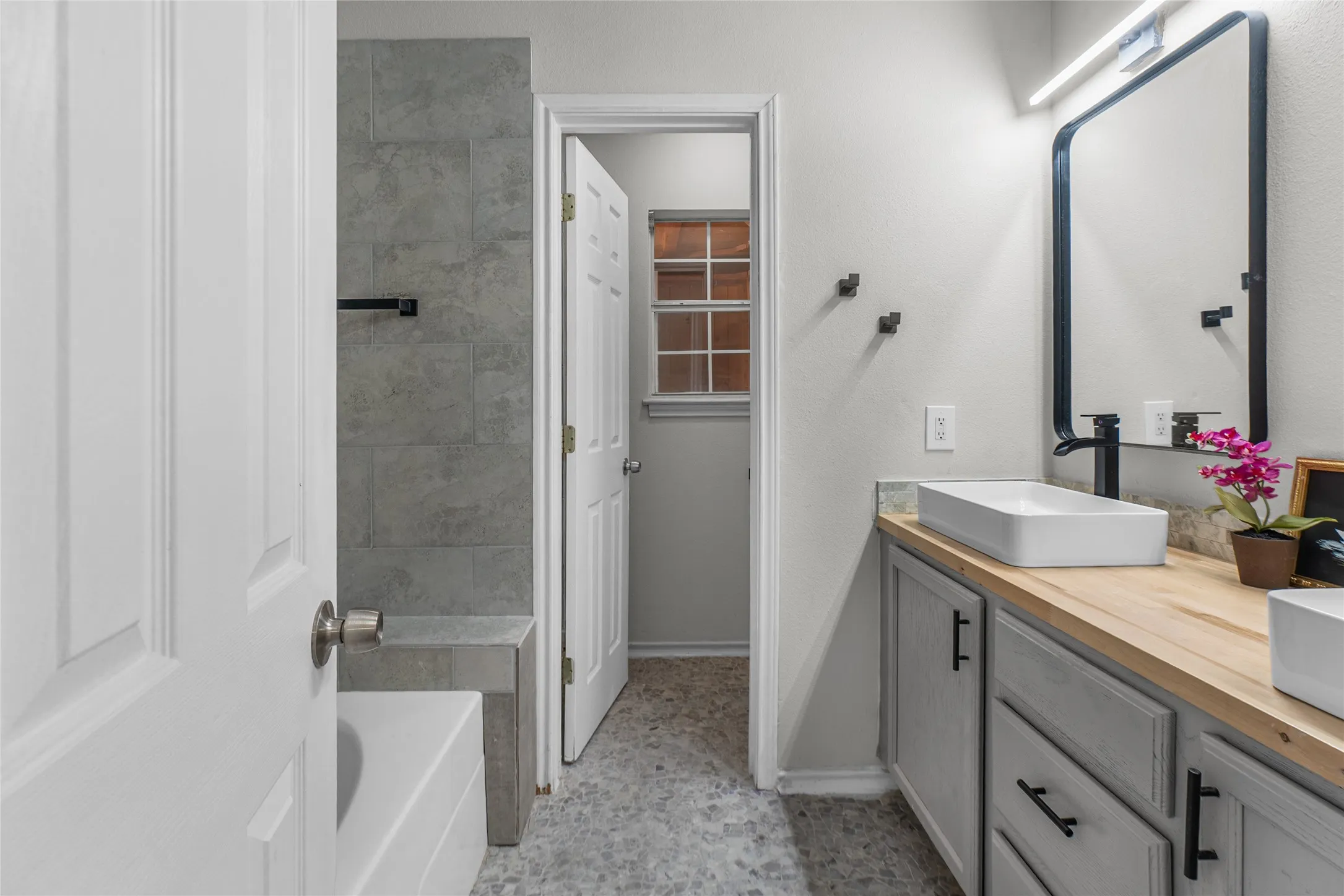 Primary Bathroom featuring a dual vanity with rectangular vessel sinks, light wood-finish countertops, and matte black fixtures