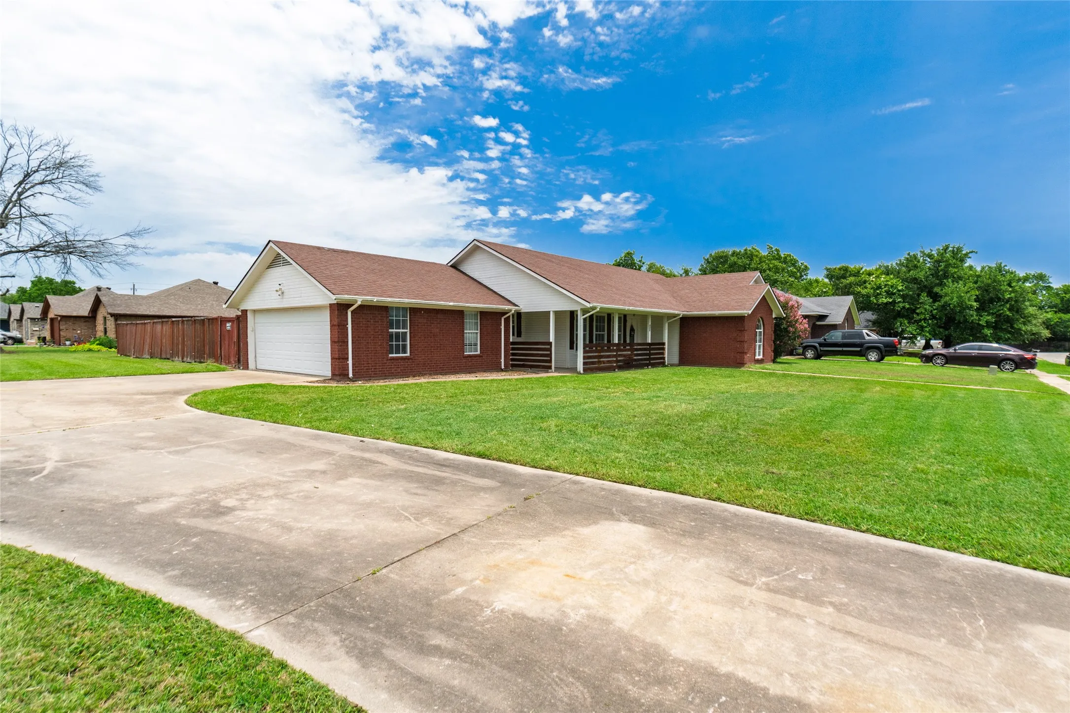 Traditional brick exterior with white trim, featuring an attached garage and a covered front porch