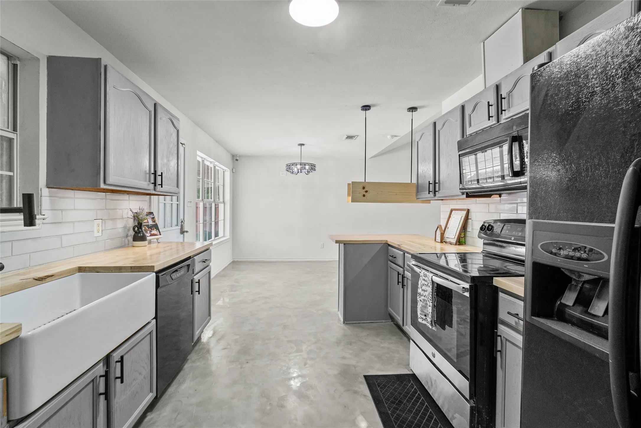 Contemporary kitchen featuring gray cabinetry, light wood-finish countertops, and a white subway tile backsplash