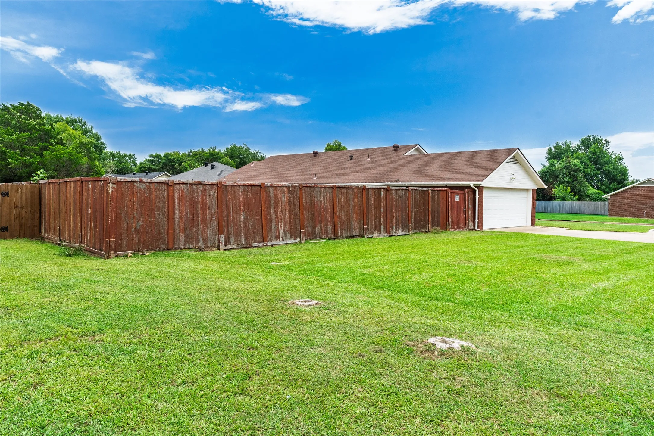 Expansive green lawn with a full privacy fence