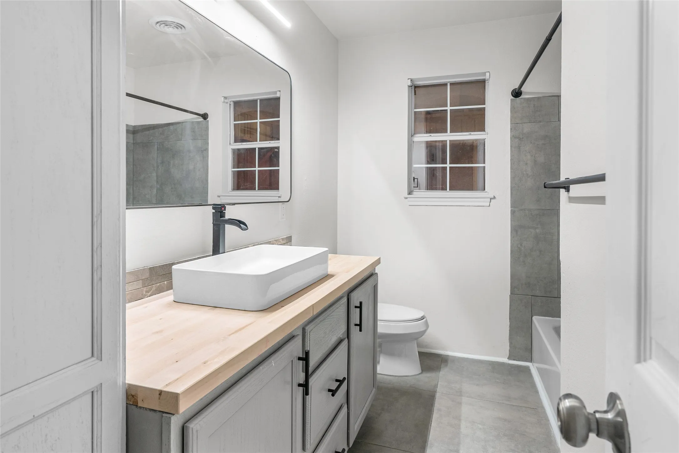 Modern bathroom featuring a rectangular vessel sink, wood-finish countertop, and matte black faucet