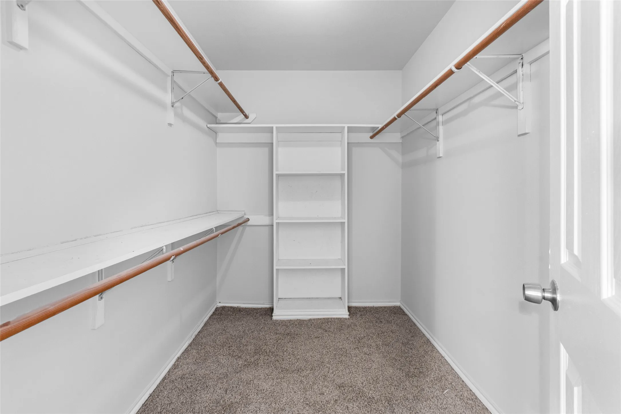 Primary Walk-in closet featuring built-in shelving, two hanging rods, and an overhead light fixture