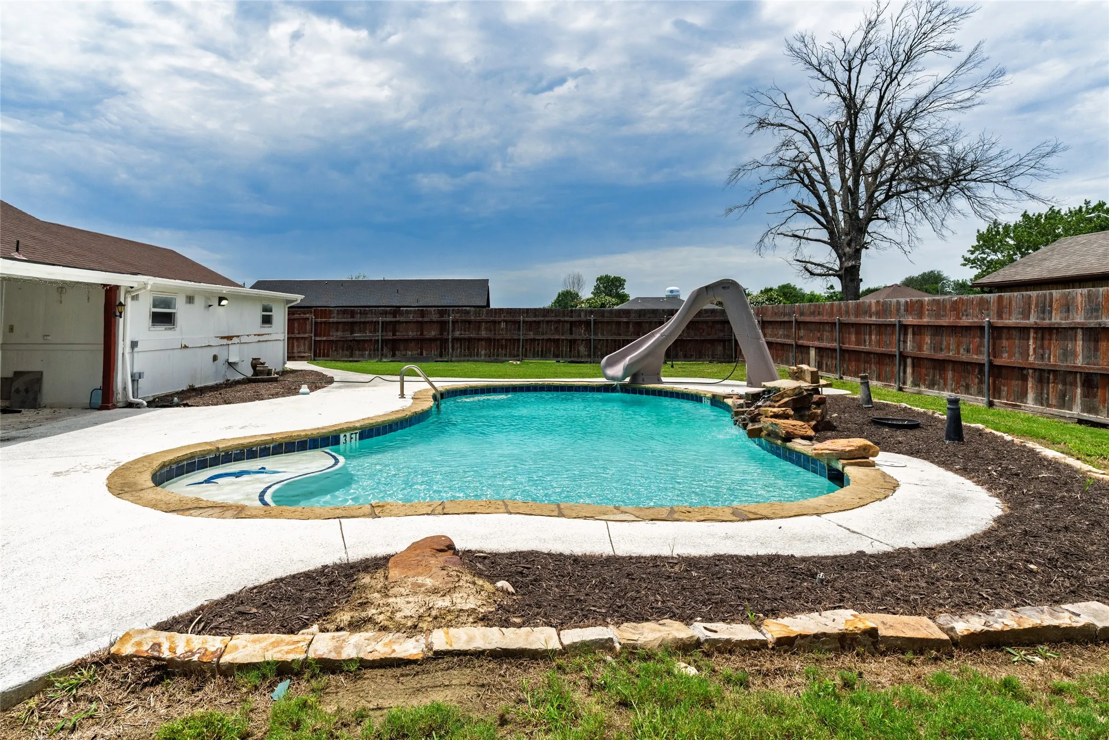 Backyard swimming pool with stone coping and a concrete surround