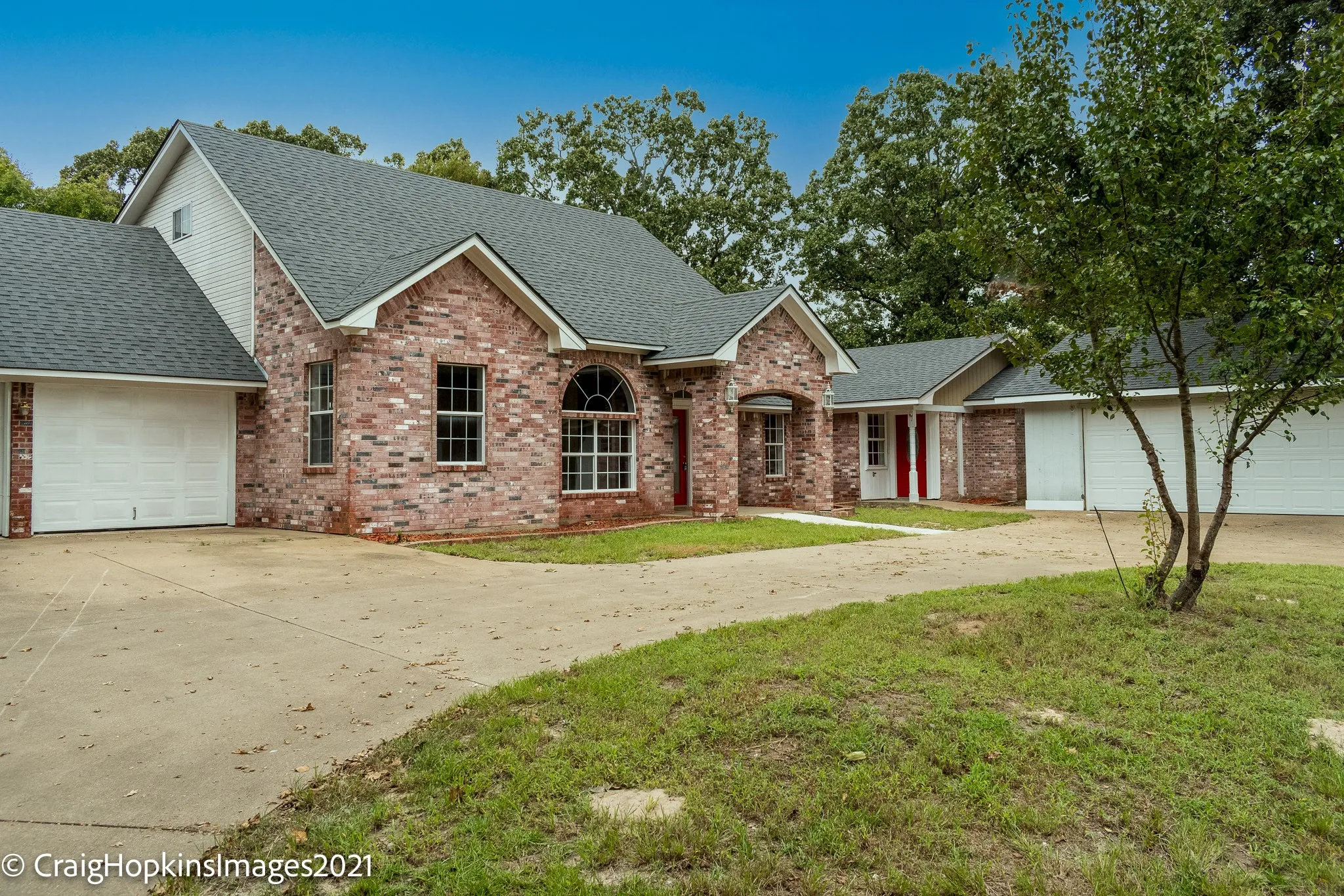Brick exterior with multiple garage bays, a prominent arched window, and a gabled roofline