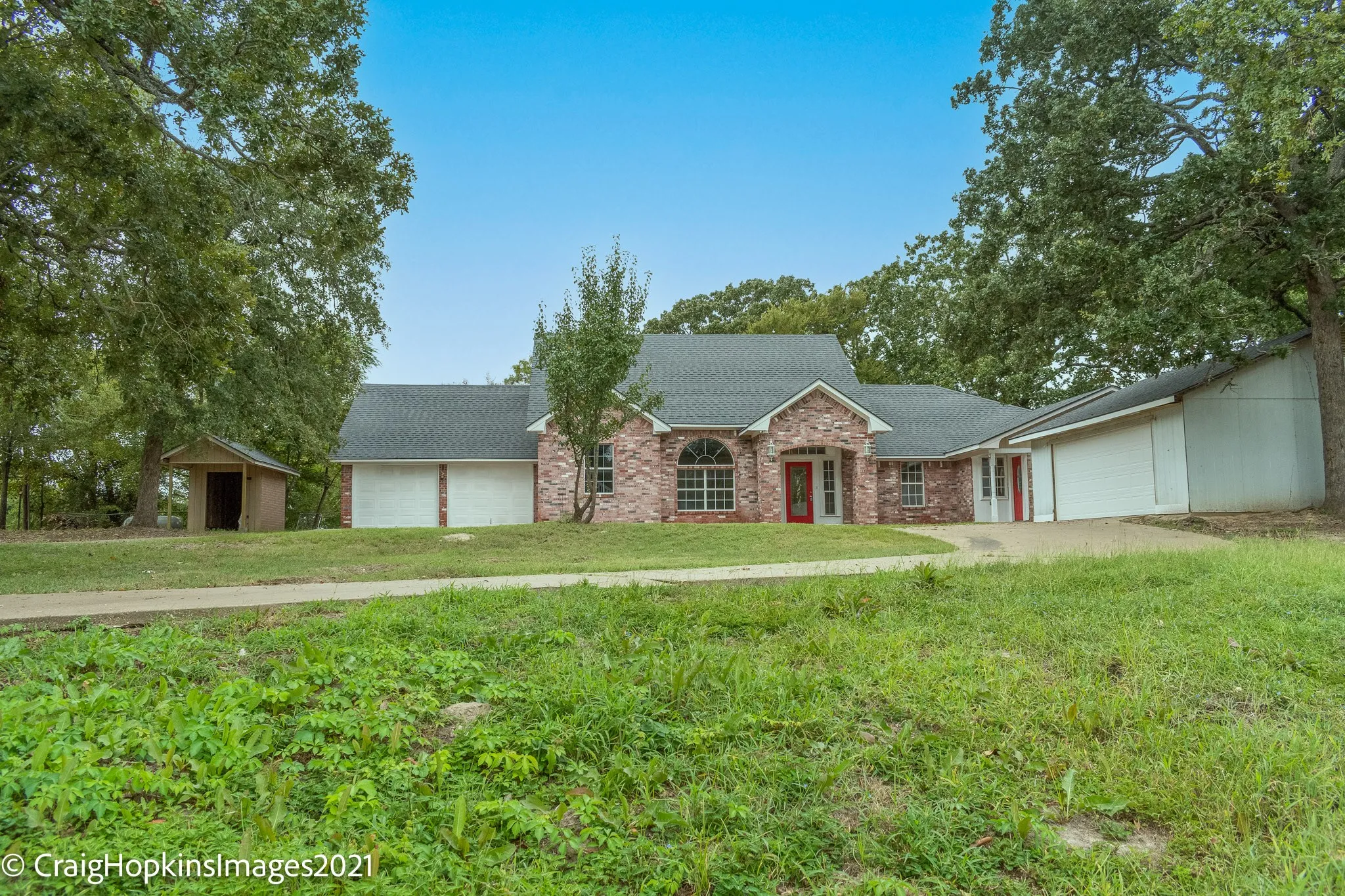 Brick exterior residence featuring a prominent arched window and a red entry door
