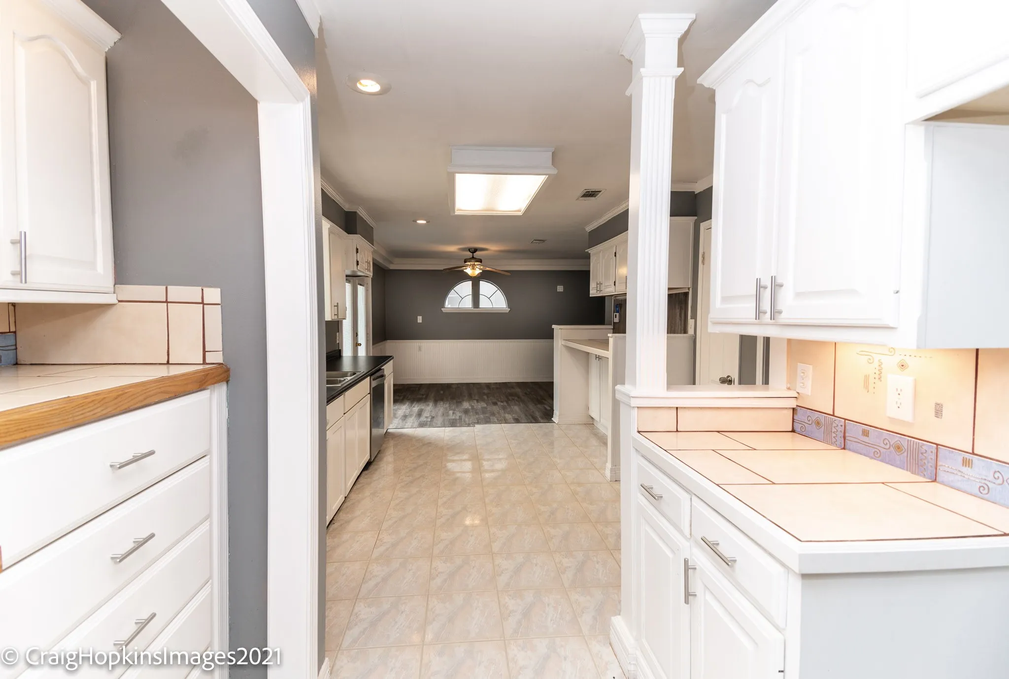 Kitchen with white cabinetry, tile countertops, and integrated appliances