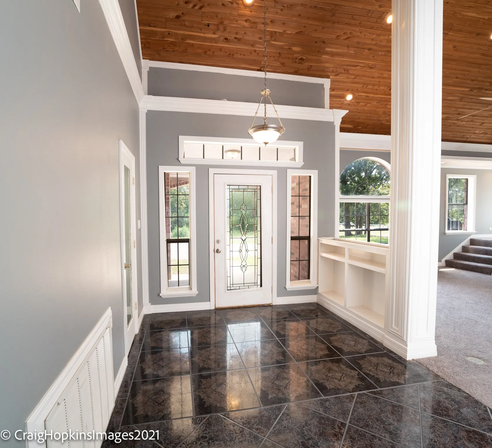 Entryway featuring dark polished tile flooring and a decorative glass-paneled door flanked by sidelight windows