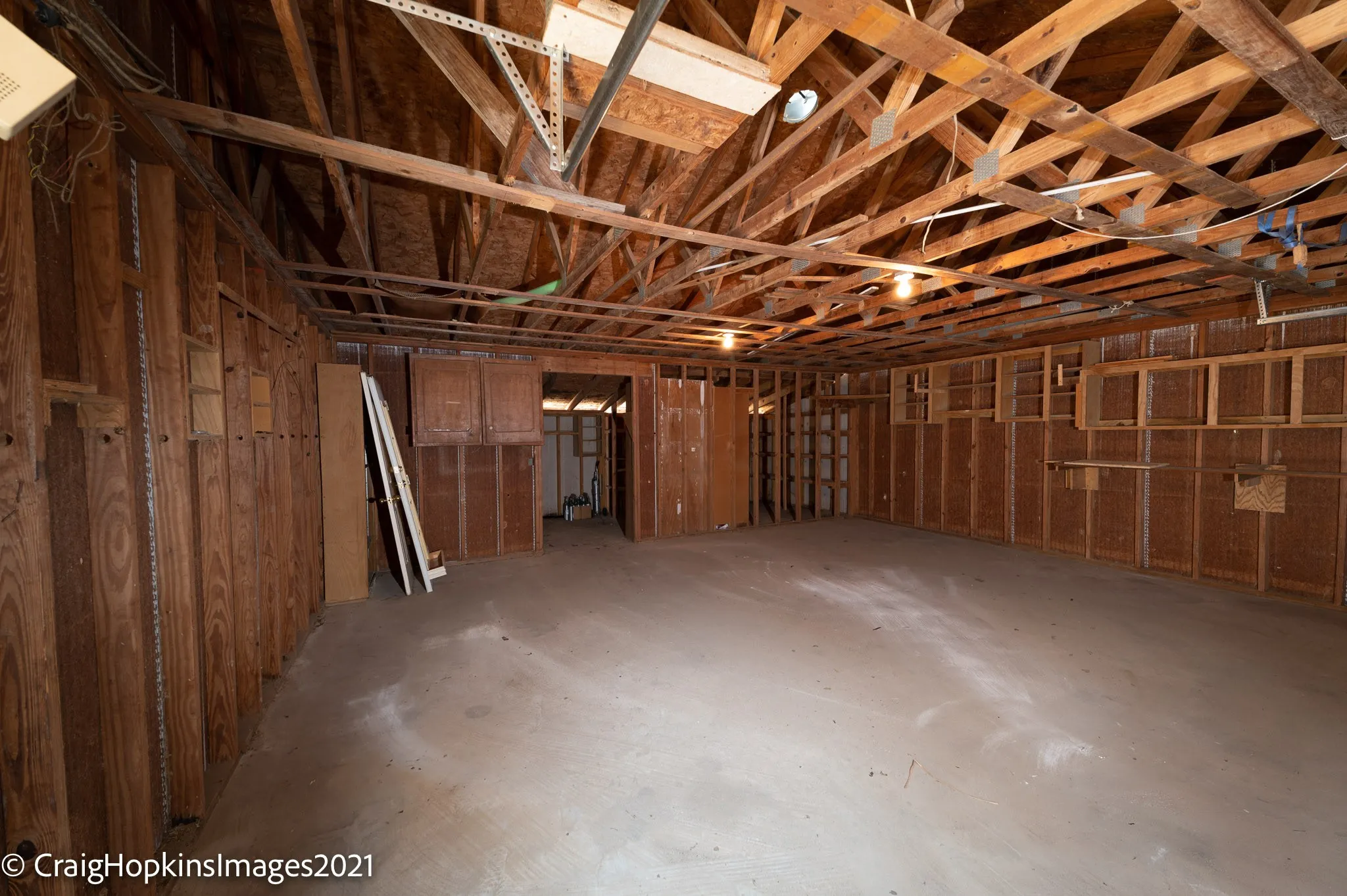 Spacious unfinished interior space featuring exposed wood framing, concrete flooring, and built-in wall cabinetry