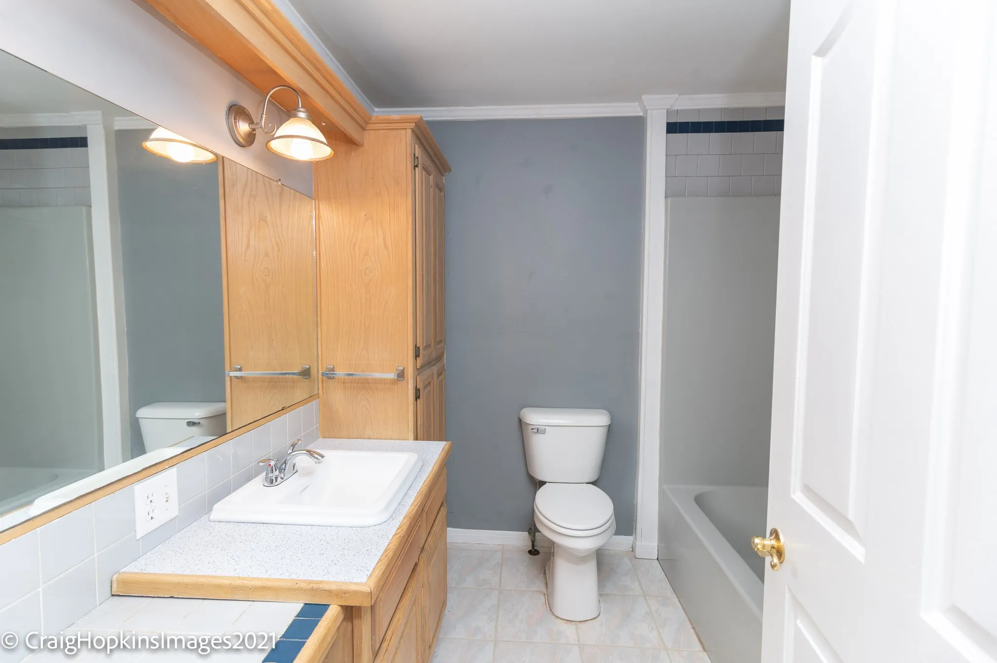 Bathroom featuring a vanity with integrated sink, wood-finish cabinetry, built-in storage, ceramic tile flooring, and a shower-tub combination with tiled surround