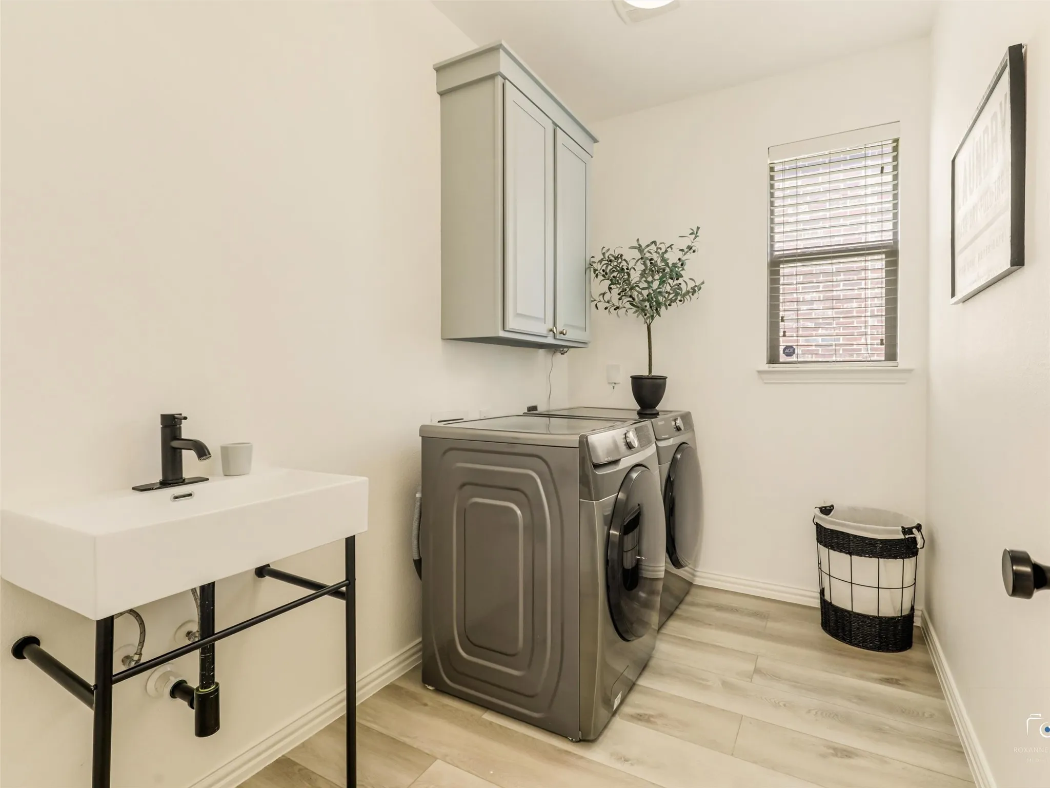 Well-designed laundry room with built-in upper cabinetry, utility sink, and modern finishes makes everyday chores convenient and organized.
