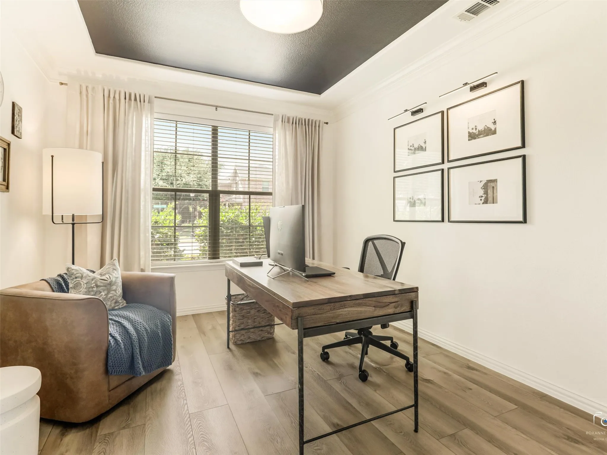 Private home office with French doors, tray ceiling, abundant natural light, and luxury vinyl plank flooring.