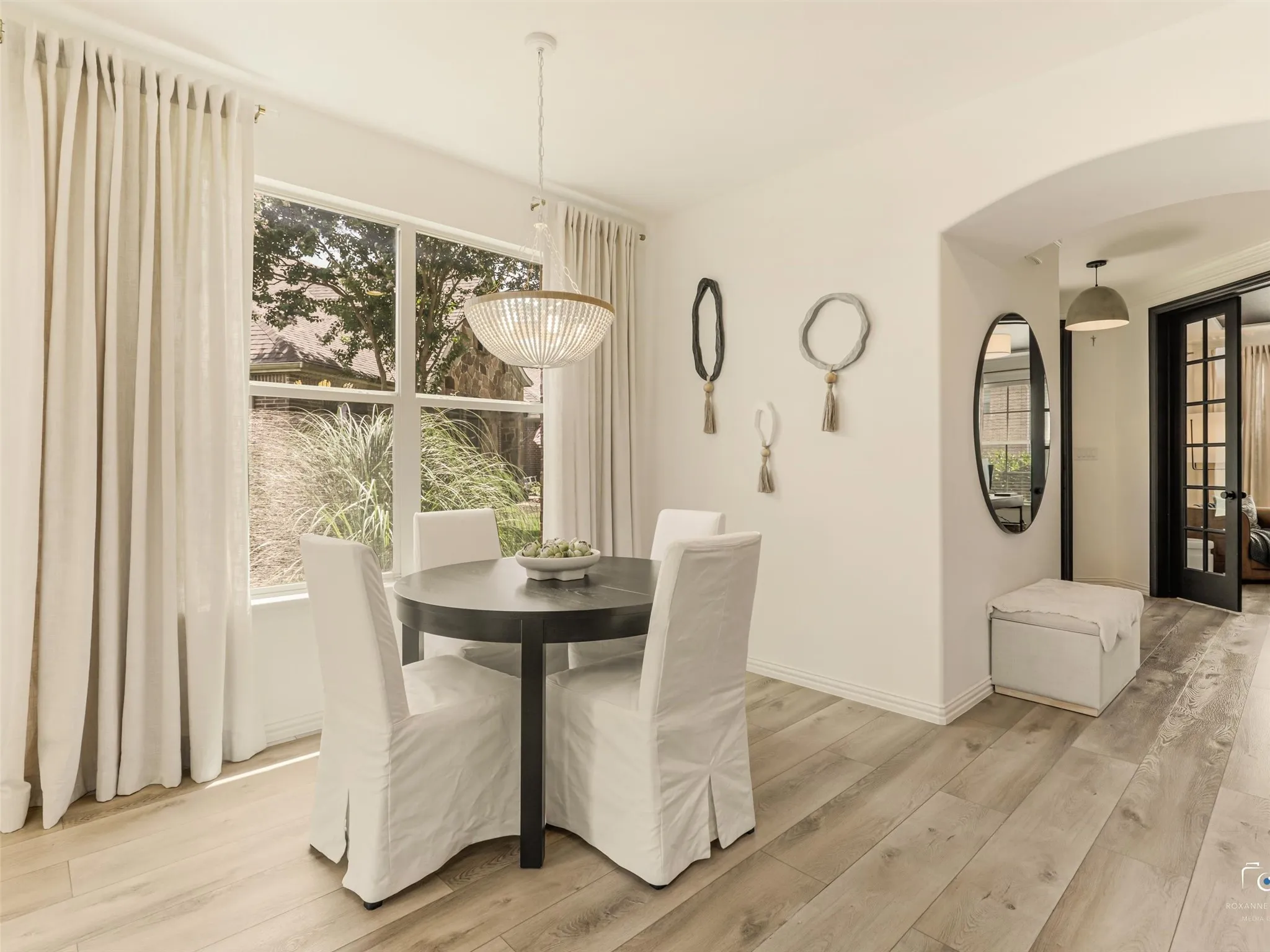 Bright dining space with designer lighting and picturesque backyard views.
