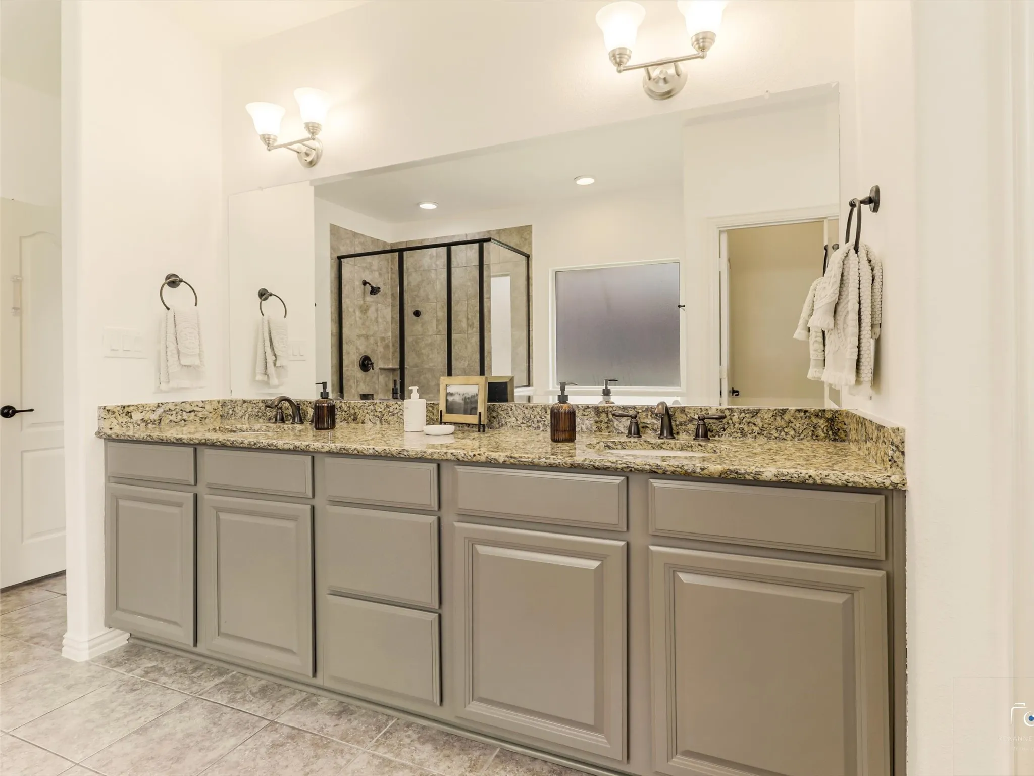 Double granite vanity provides abundant counter space and storage, creating a functional and elegant owner's bathroom.