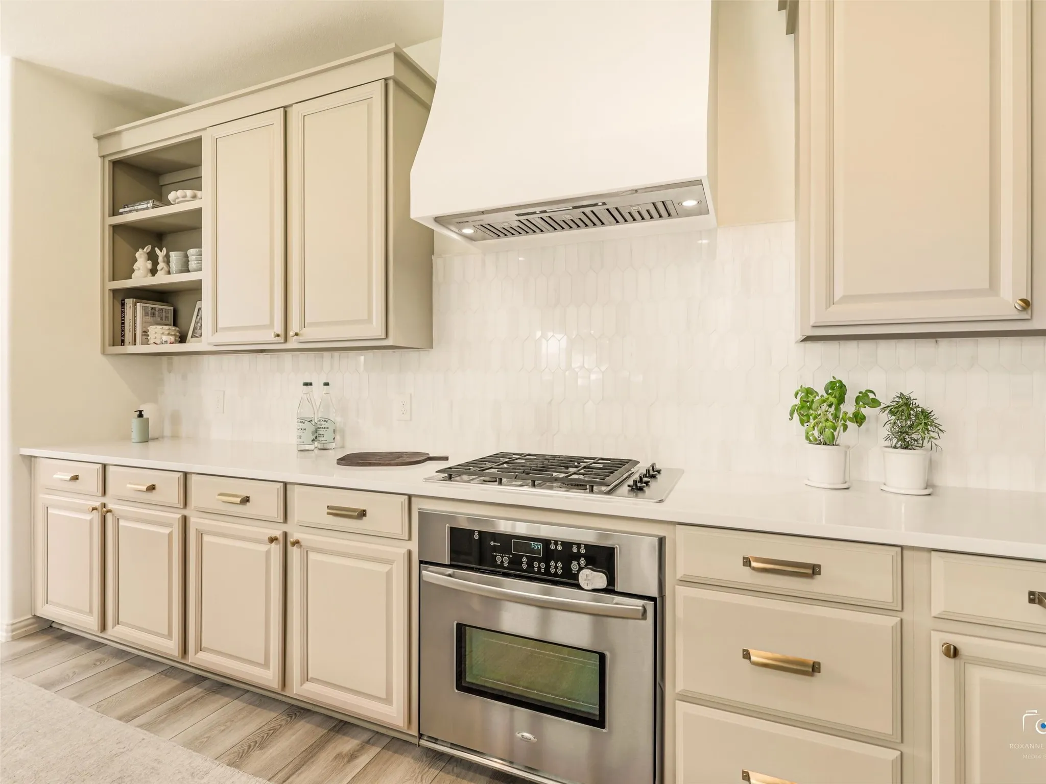Newly remodeled kitchen featuring quartz countertops, natural marble picket tile backsplash, custom vent hood, stainless steel appliances, and abundant cabinetry.