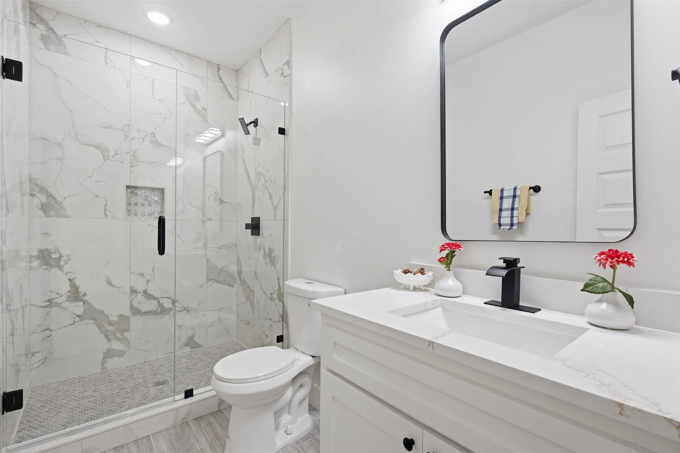Shower with clear glass enclosure and marble-style tile surround
