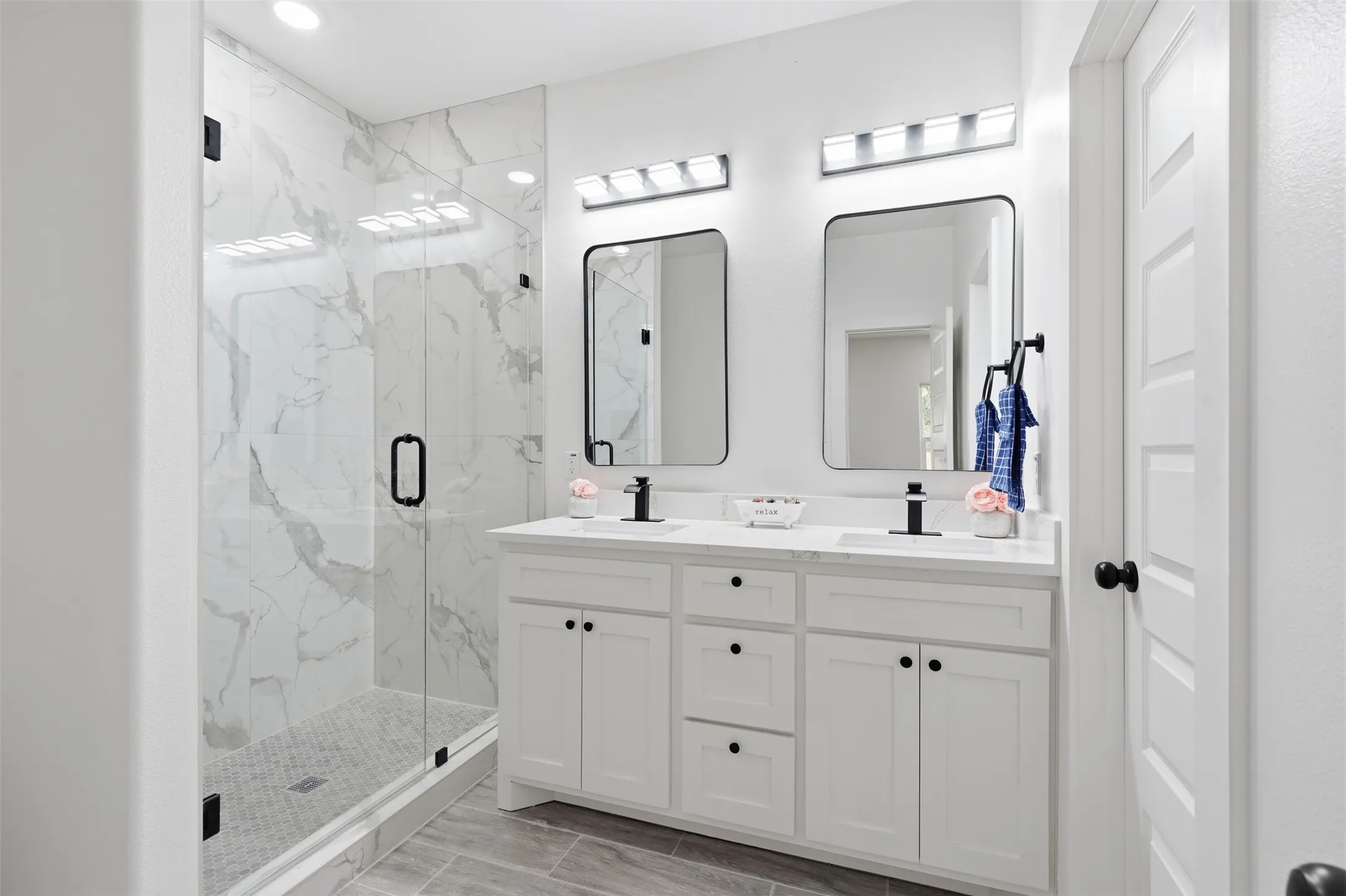 Bathroom featuring a dual vanity with white cabinetry, integrated sinks, and black matte fixtures