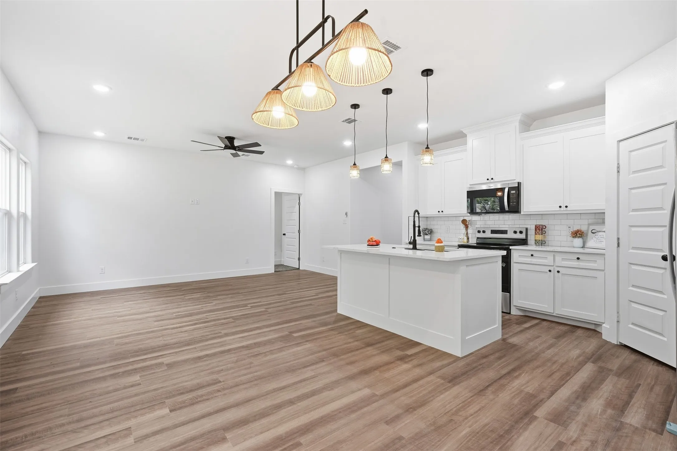 Open-concept living space featuring wood-finish flooring, white walls, and recessed lighting