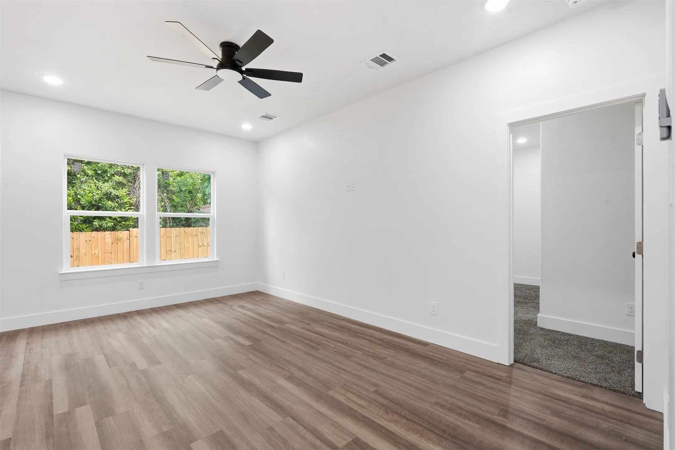 Spacious room featuring wood-finish flooring, recessed lighting, and a contemporary ceiling fan