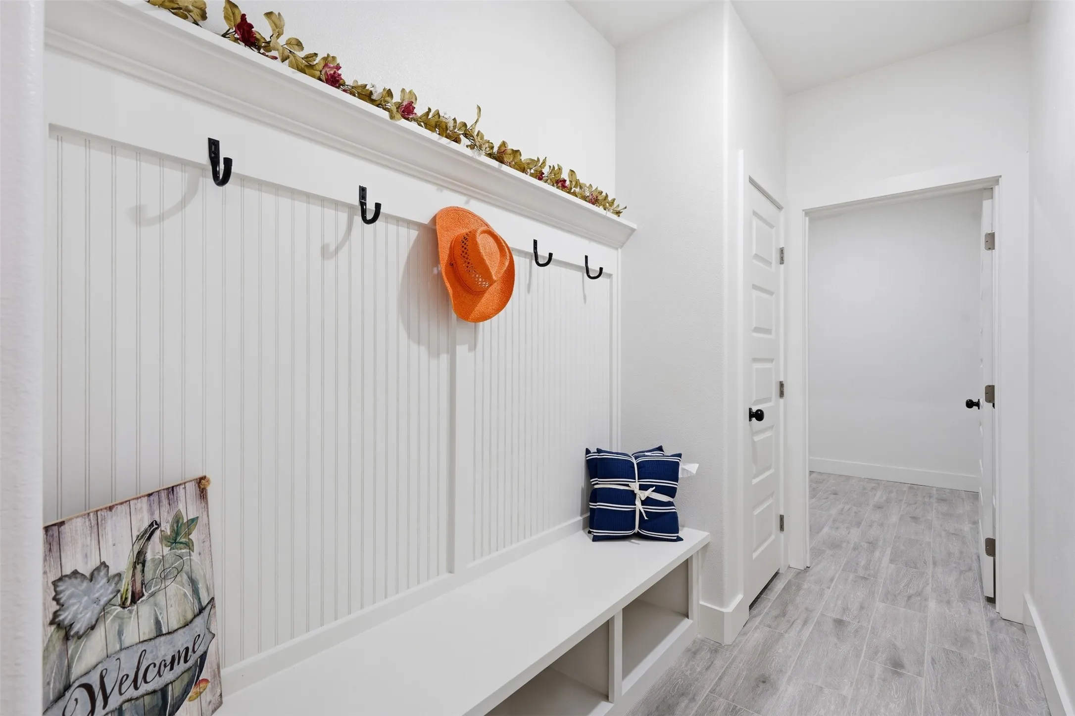 Entryway featuring a built-in bench with integrated shelving, beadboard paneling, and a display ledge