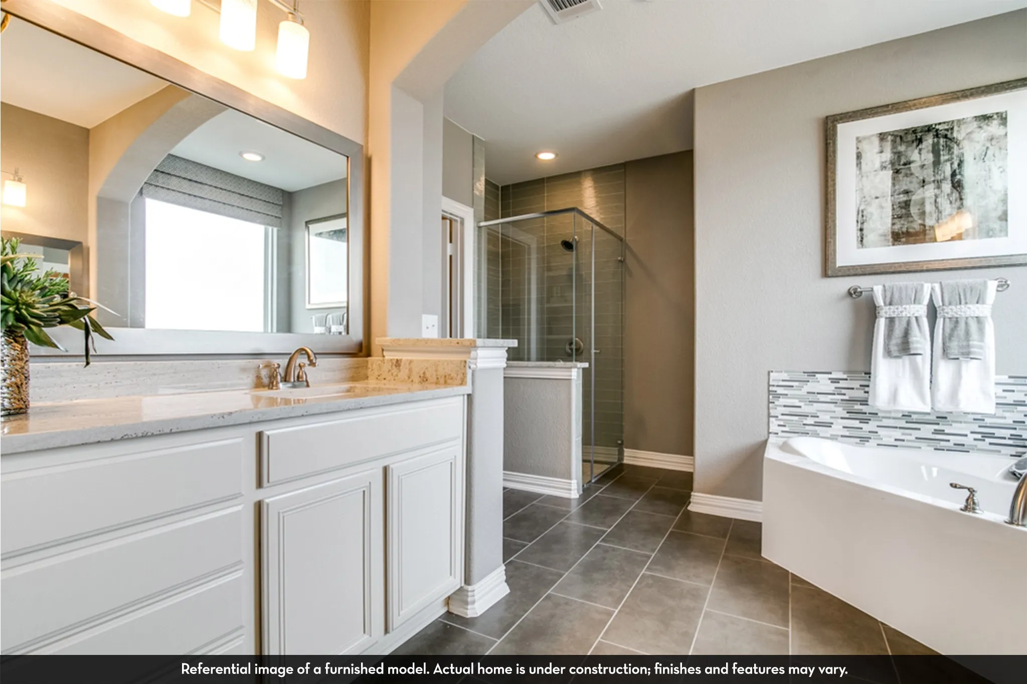 Bathroom featuring a corner soaking tub with mosaic tile surround, a separate glass-enclosed shower, a double vanity with stone countertops and undermount sinks, and tile flooring