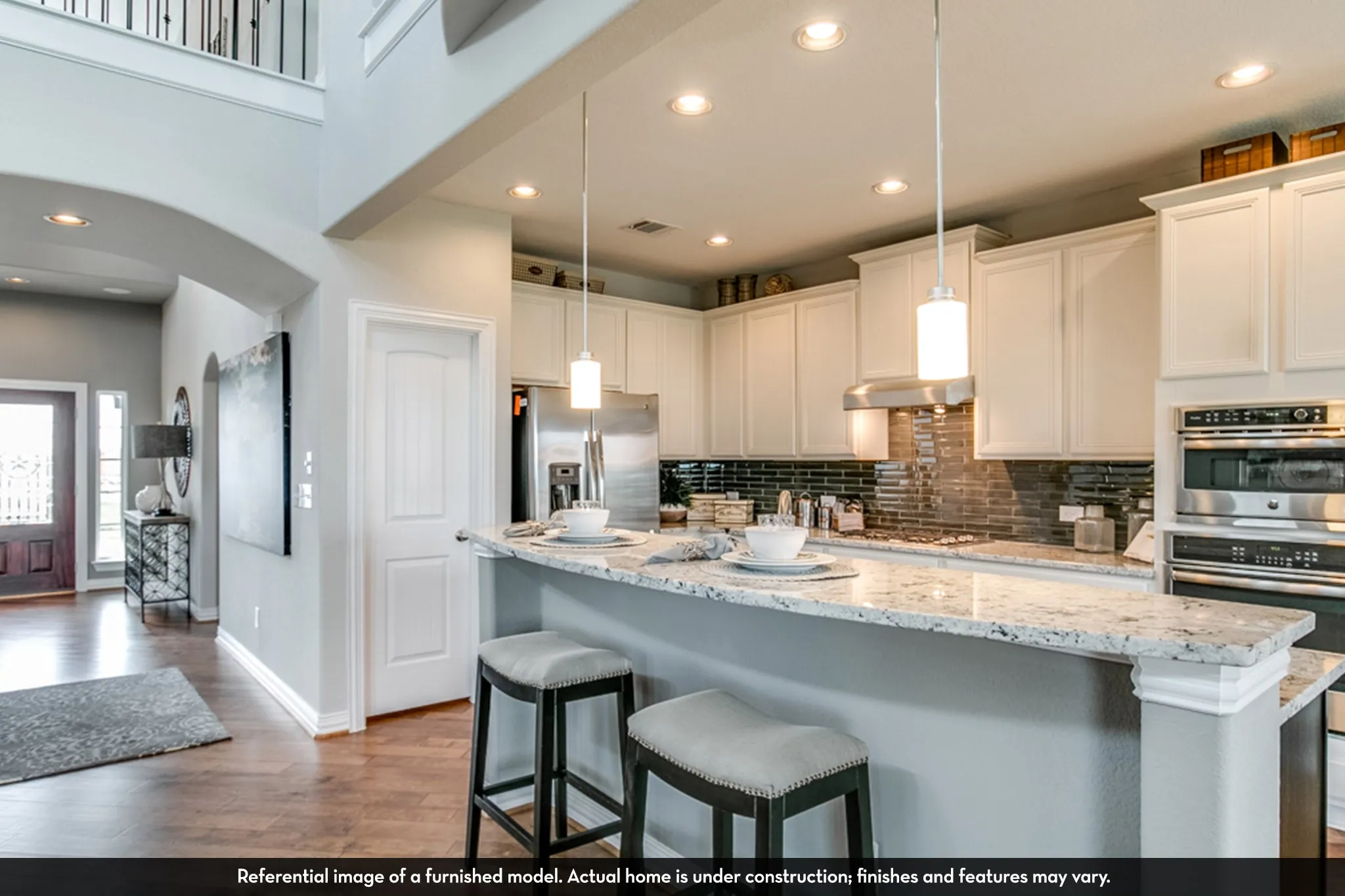 Open-concept kitchen featuring an eat-at island with a granite-style countertop, white cabinetry, stainless steel appliances, and pendant lighting