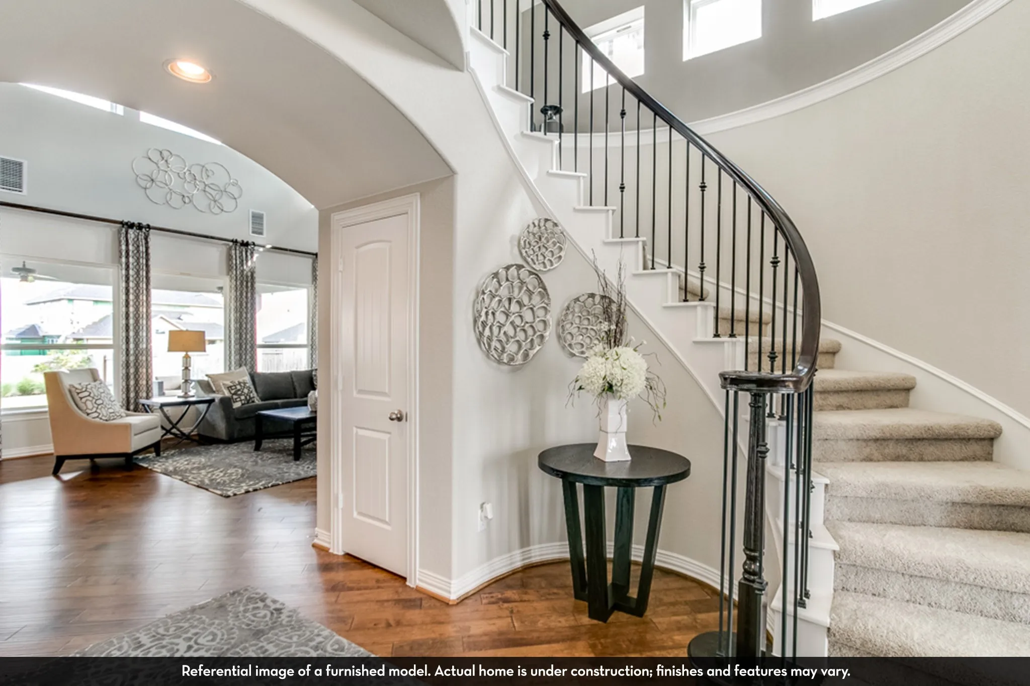 Grand curved staircase featuring dark wood railing and wrought iron balusters