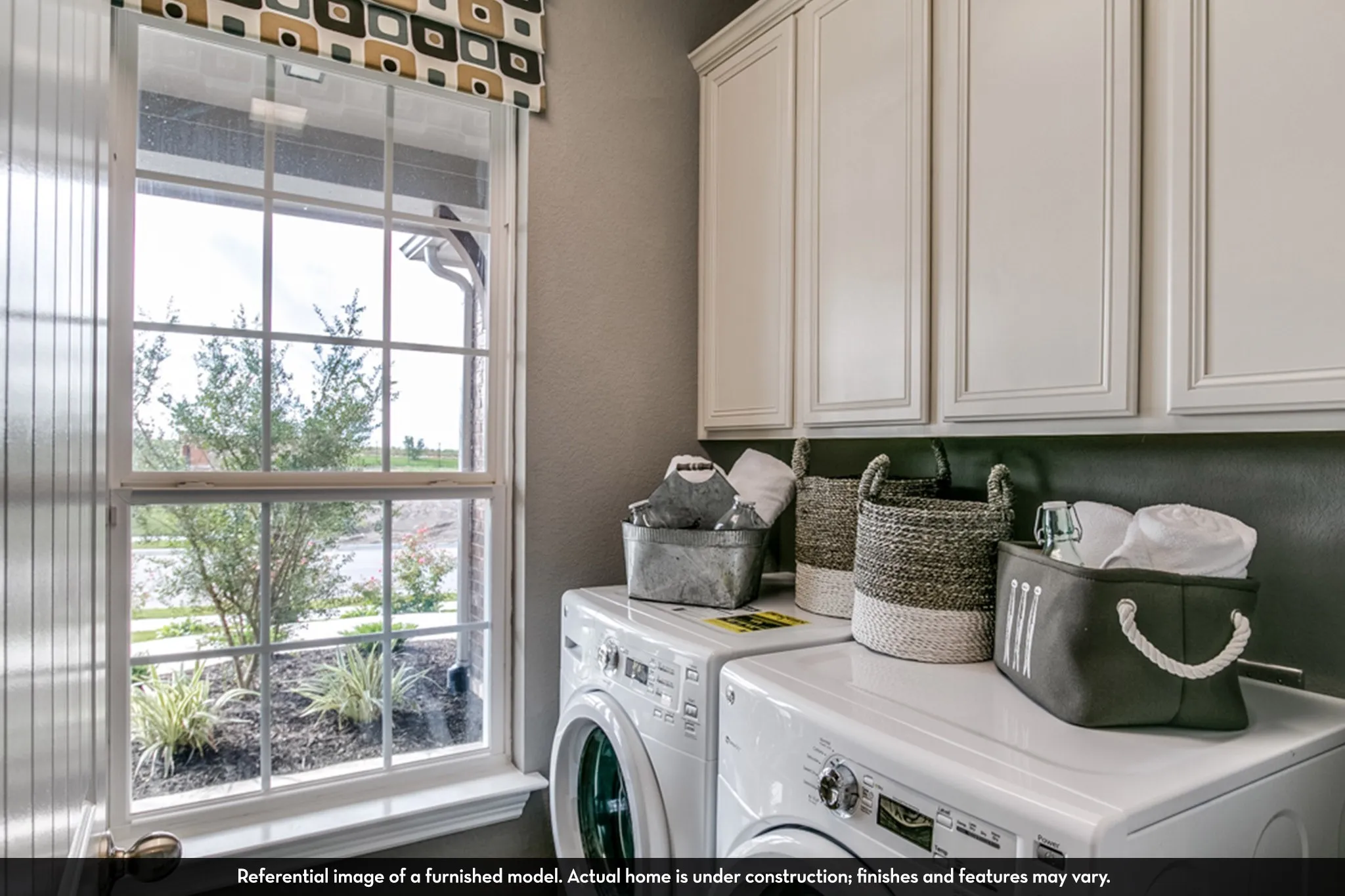 Laundry area featuring upper cabinetry with panel doors, a large window with grilles, and a window sill