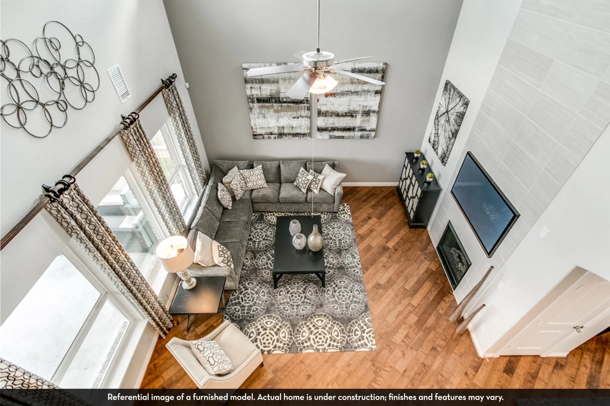 Vaulted ceiling great room featuring wood-finish flooring, a contemporary fireplace, and a ceiling fan with integrated lighting