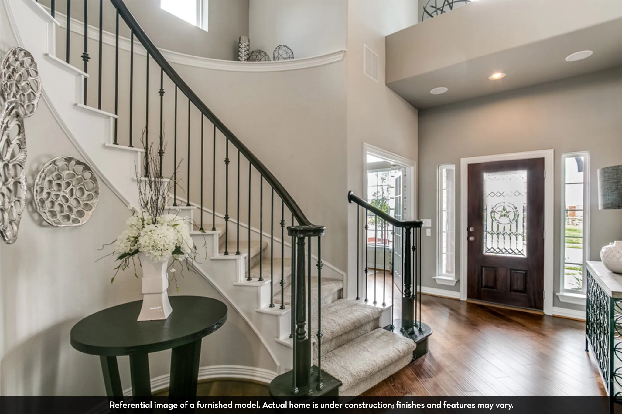 Grand entryway featuring a curved staircase with wrought iron balusters and carpeted treads