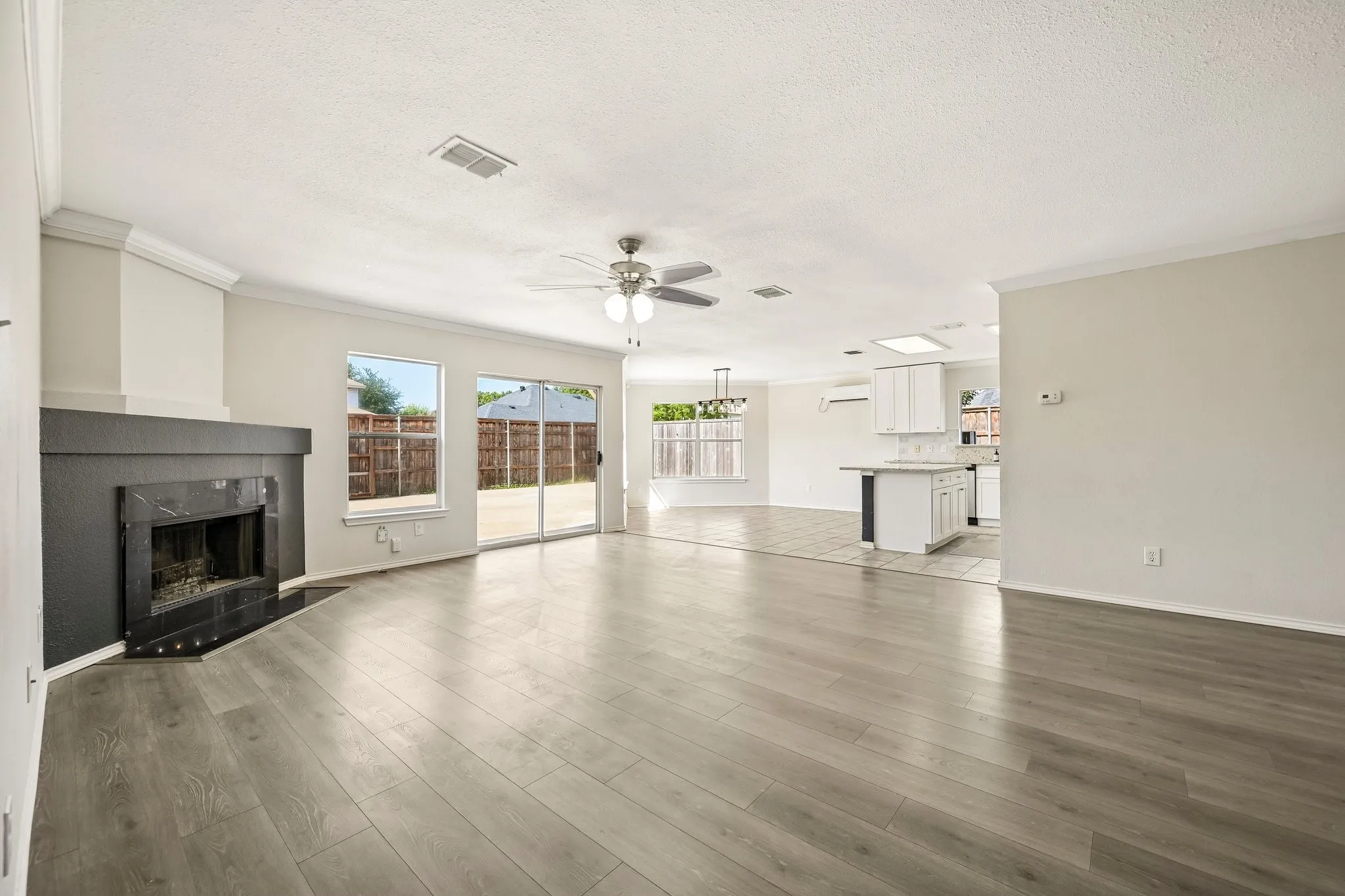Spacious interior featuring wood-finish flooring and a fireplace with a dark stone surround